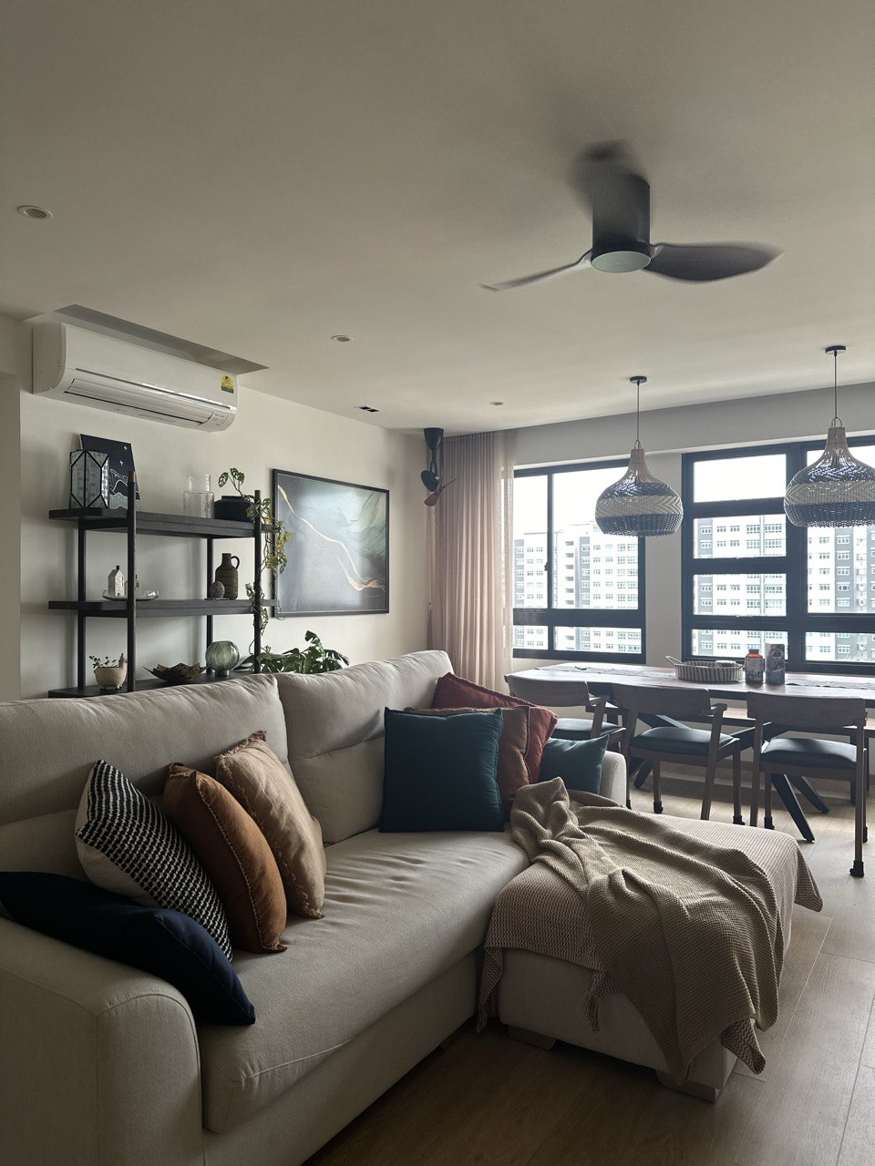 Home Hunt Chronicles: The Resale Route - Modern living room with beige sofa, cozy cushions, large window with city view