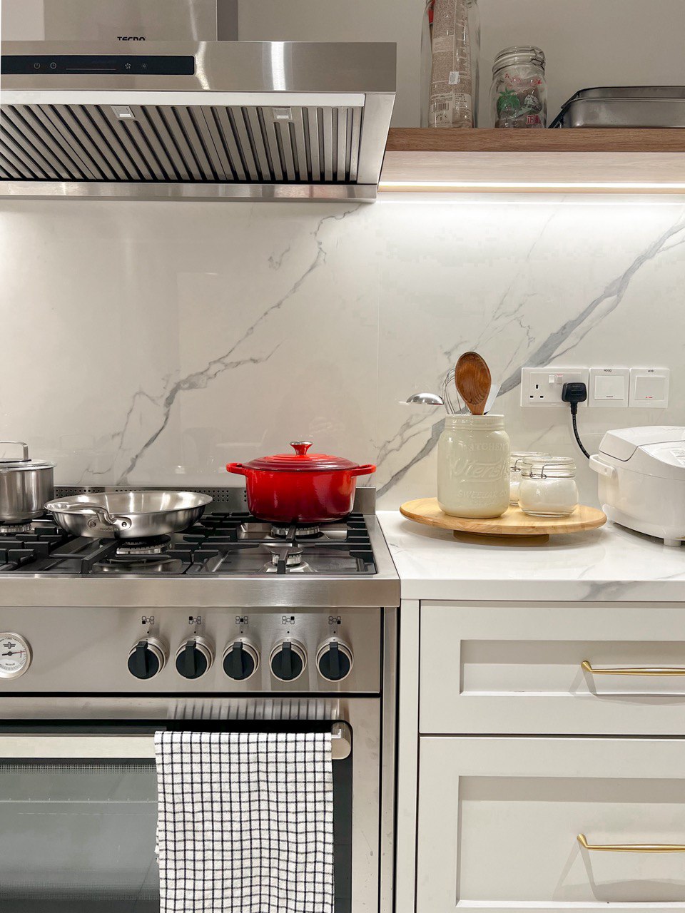 A Modern Farmhouse - Stainless steel kitchen, modern design, gas stove, red pot on top, white marble backsplash, stainless