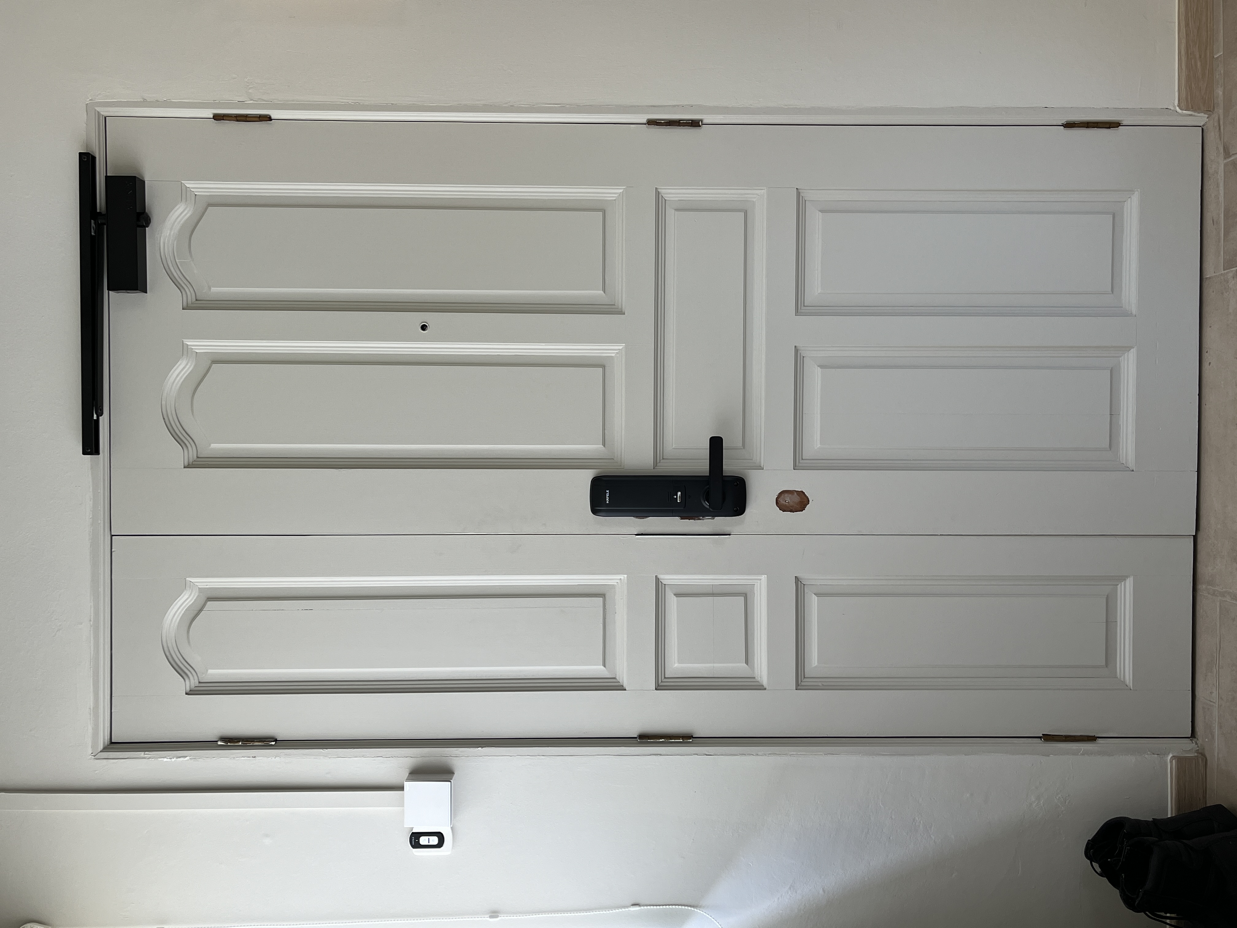 Entryway - Clean & Simple - White door with decorative paneling, black door handle, small brown knob, modern lock mechanism