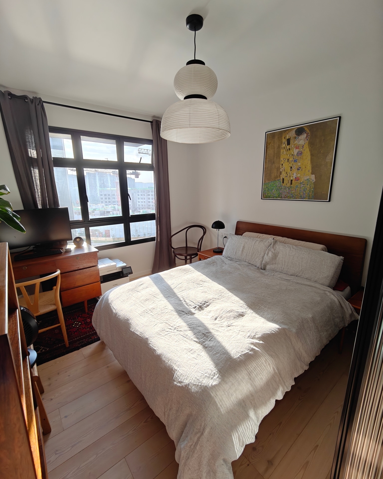 Dream A Little Dream Of Me - Modern bedroom with large window, natural light, wooden floor, beige bedspread, black desk