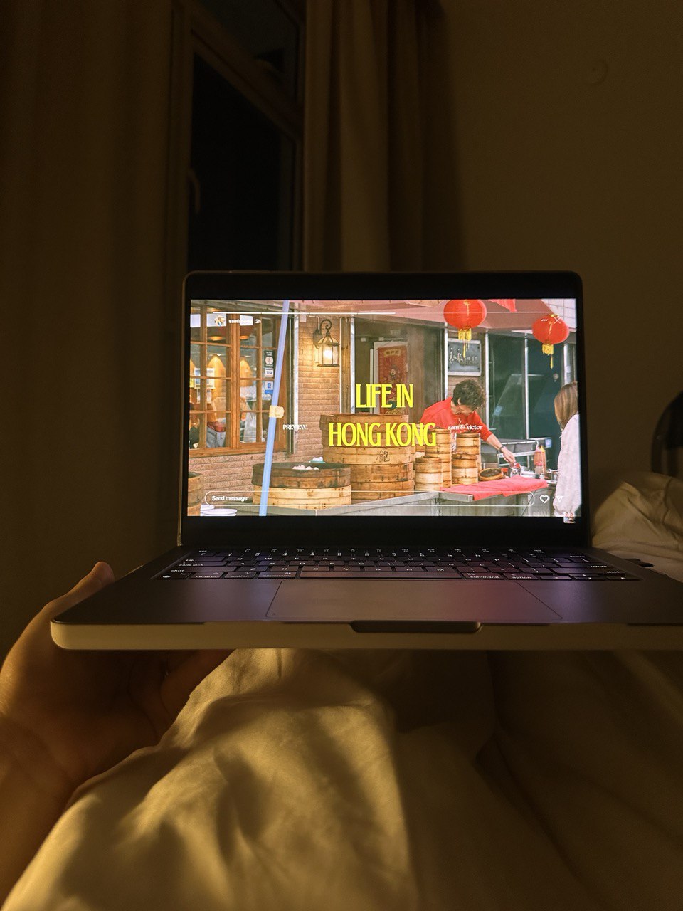 Minimal Bedroom: Our place to unwind and relax  - Laptop screen displaying "Life in Hong Kong, " dimly lit room, person in