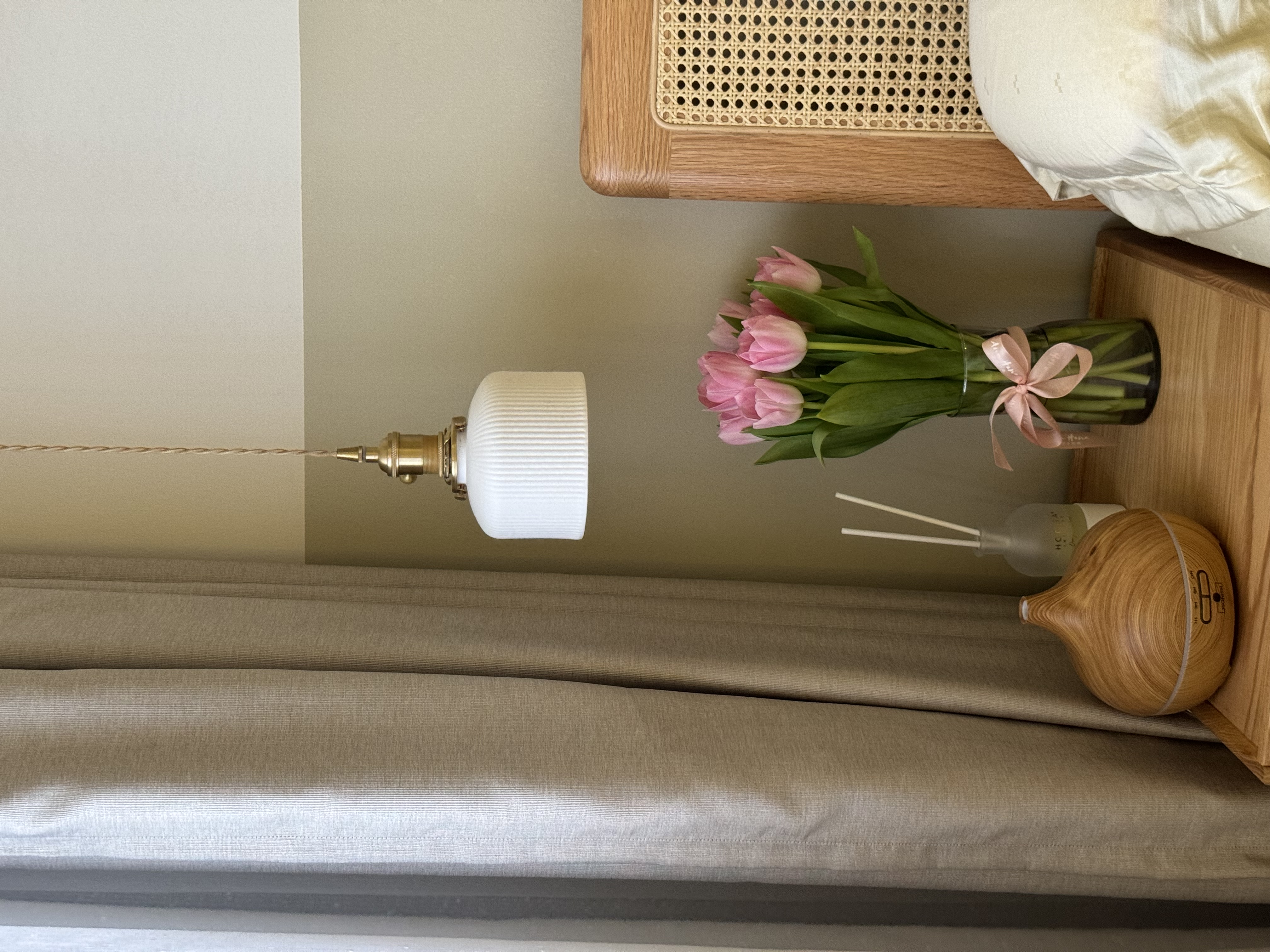 A Glimpse into Our Cozy Master Bedroom Sanctuary 🛏️🌙 - White textured lamp, wooden shelf, pink tulips, green stems, pink