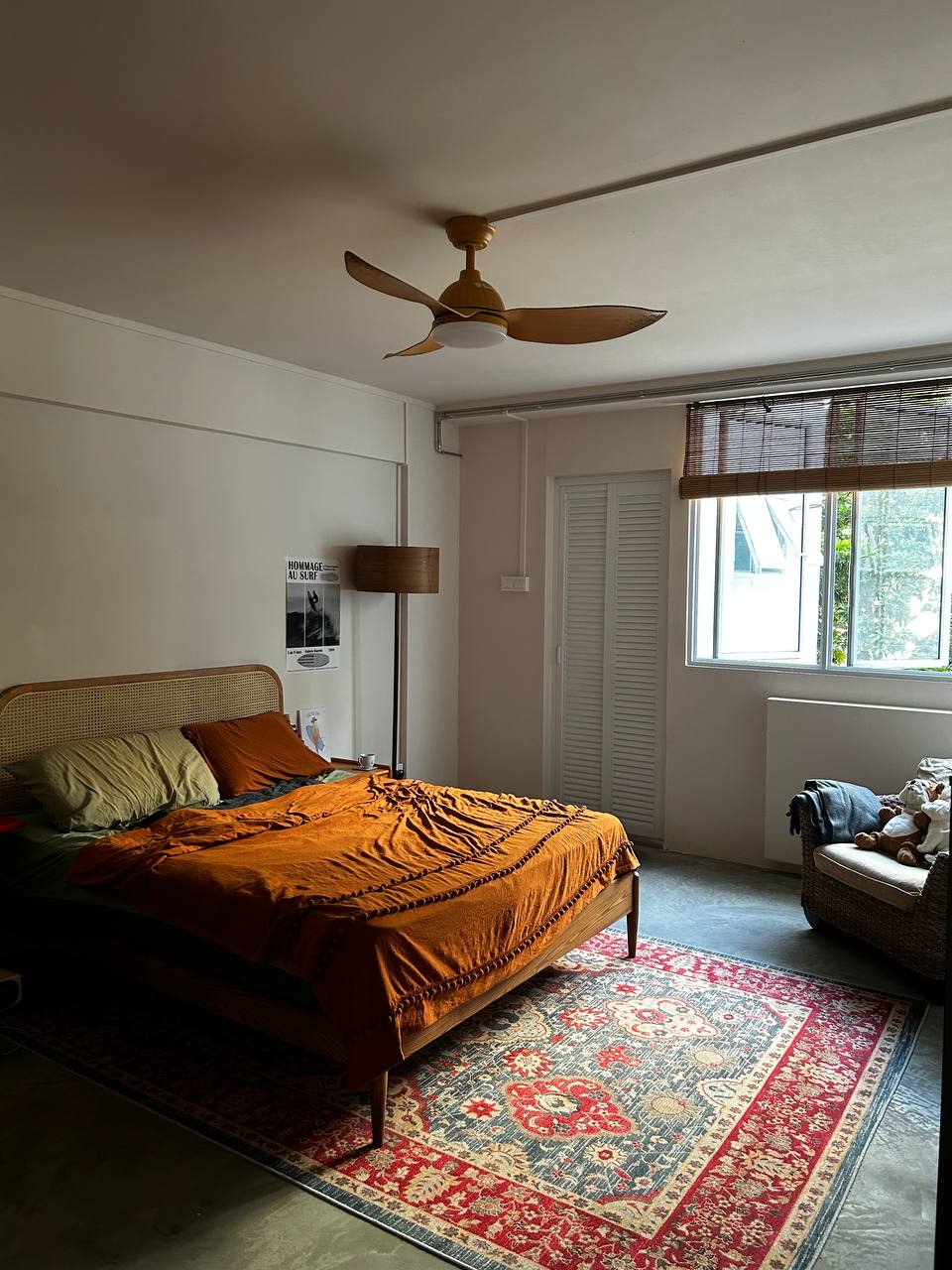 Master Bedroom: Where Nothing Really Mattress - Sunlit bedroom with cozy bed, orange comforter, wooden floor, patterned rug