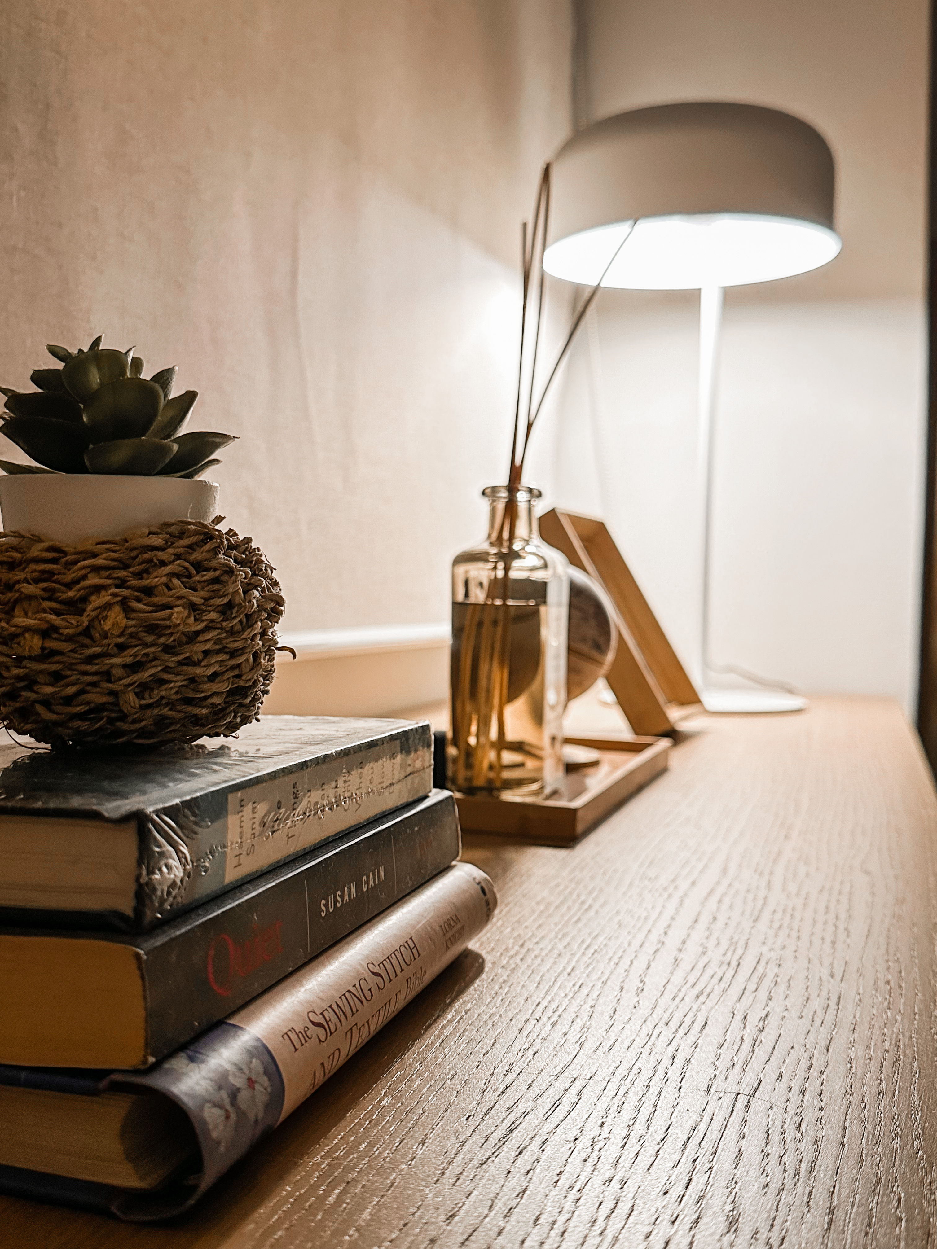 Warm fuzzy cosy nook to wind down - Sedan, wooden table, cozy, warm lighting, indoor setting, books, stack, decorative items
