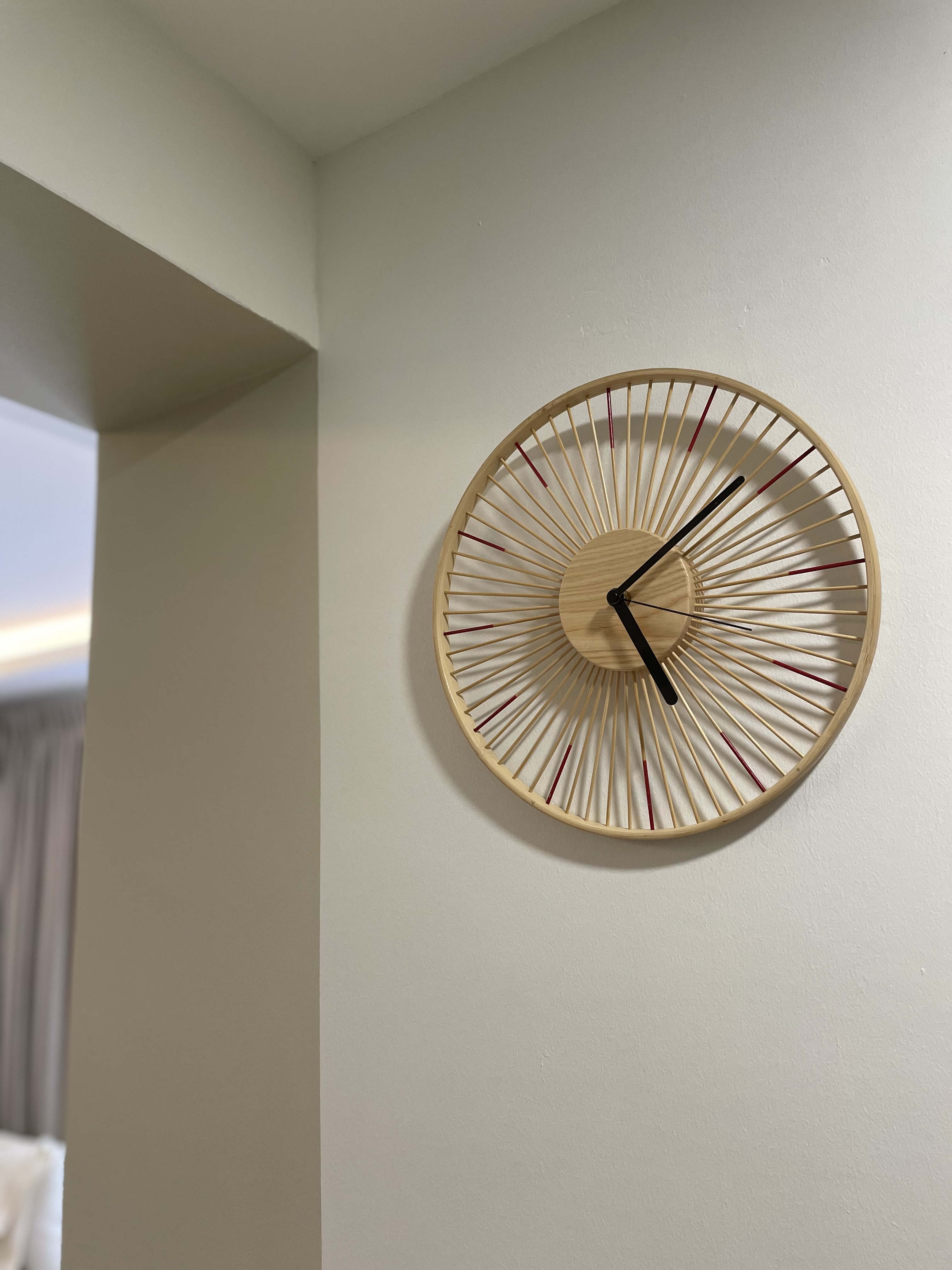 Living Room: Embracing Nordic Warmth with Wooden and Rattan Accents - Wooden wall clock with radial design, minimalist style