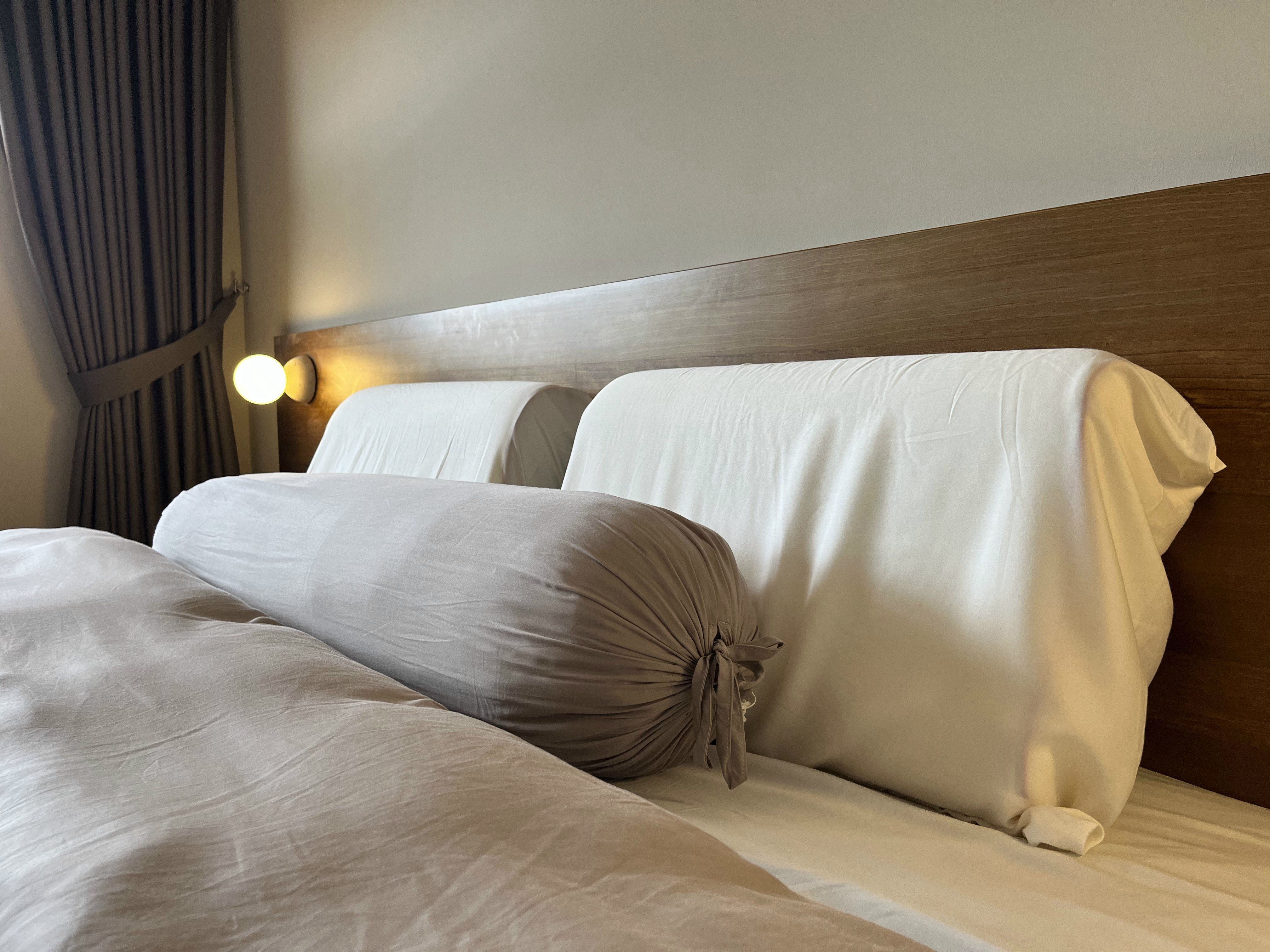 Welcome Home: A "Sand-sory" Escape - Soft, neutral-toned bedding, elegant headboard, draped curtains, warm lighting