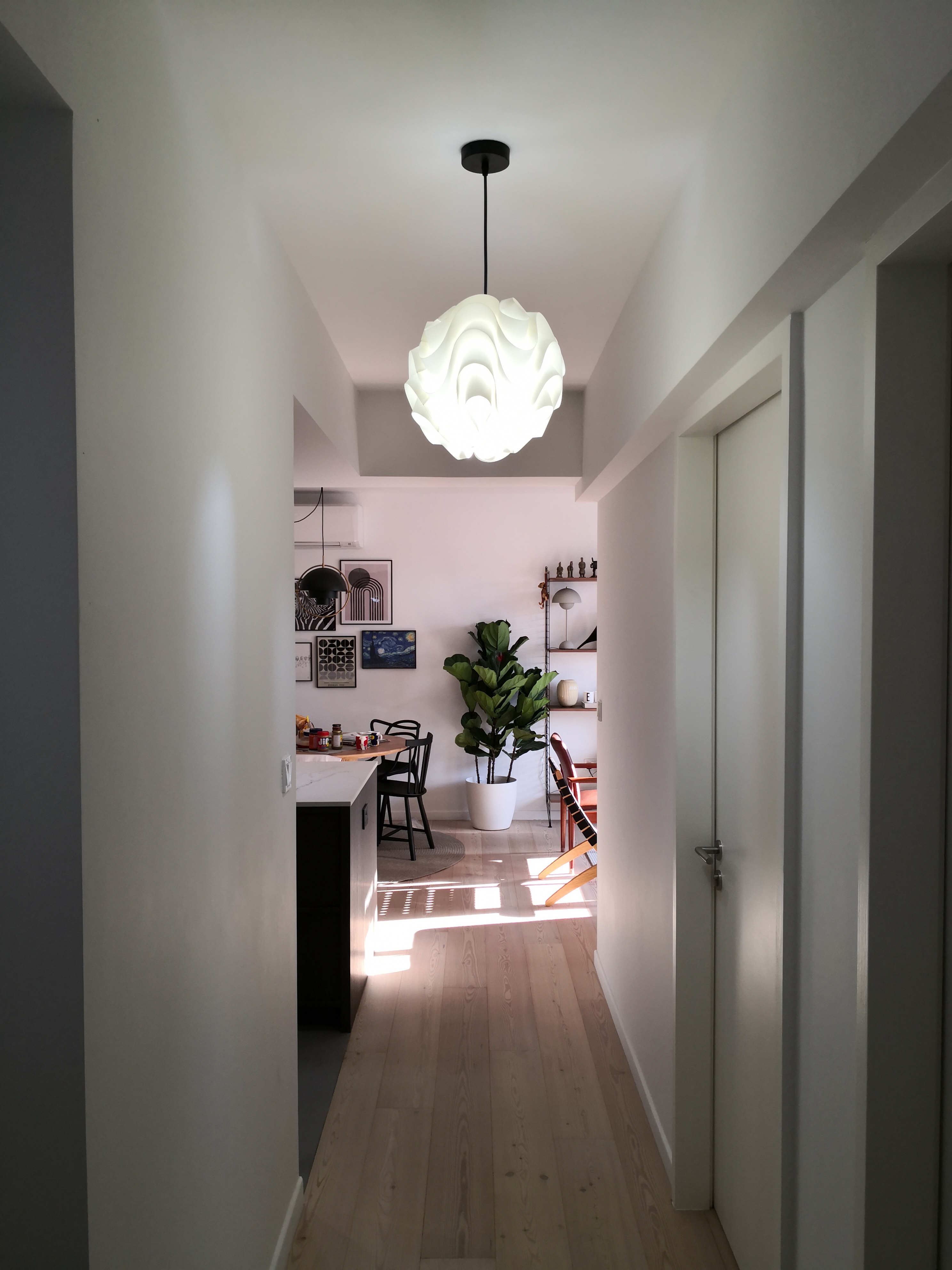 Confessions of a Serial Plant Killer - Modern minimalist kitchen with sleek black pendant light fixture, light wooden floor