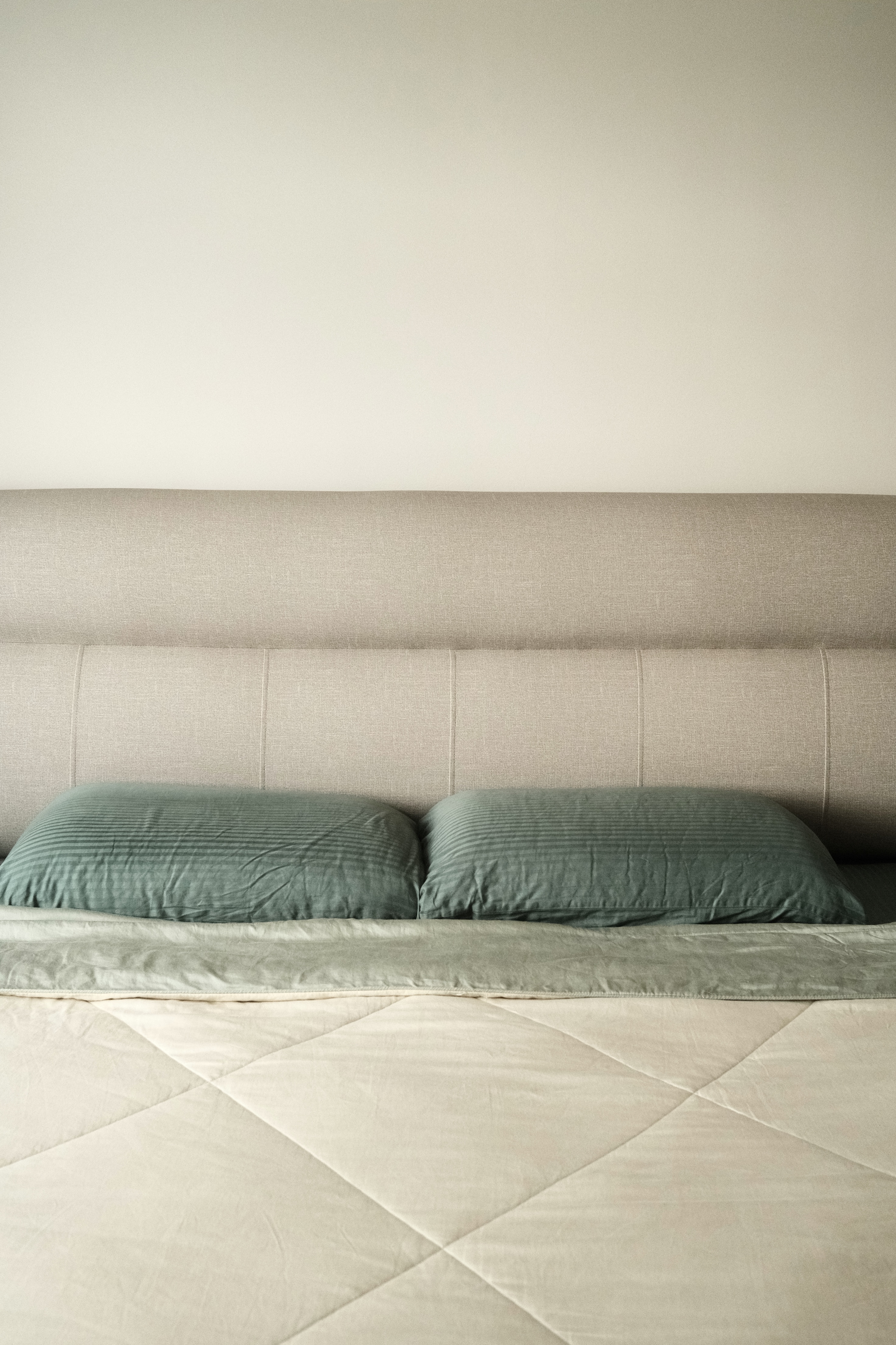 Our serene bedroom with minimal carpentry - Beige upholstered headboard, green pillows, quilted beige bedspread, minimalist