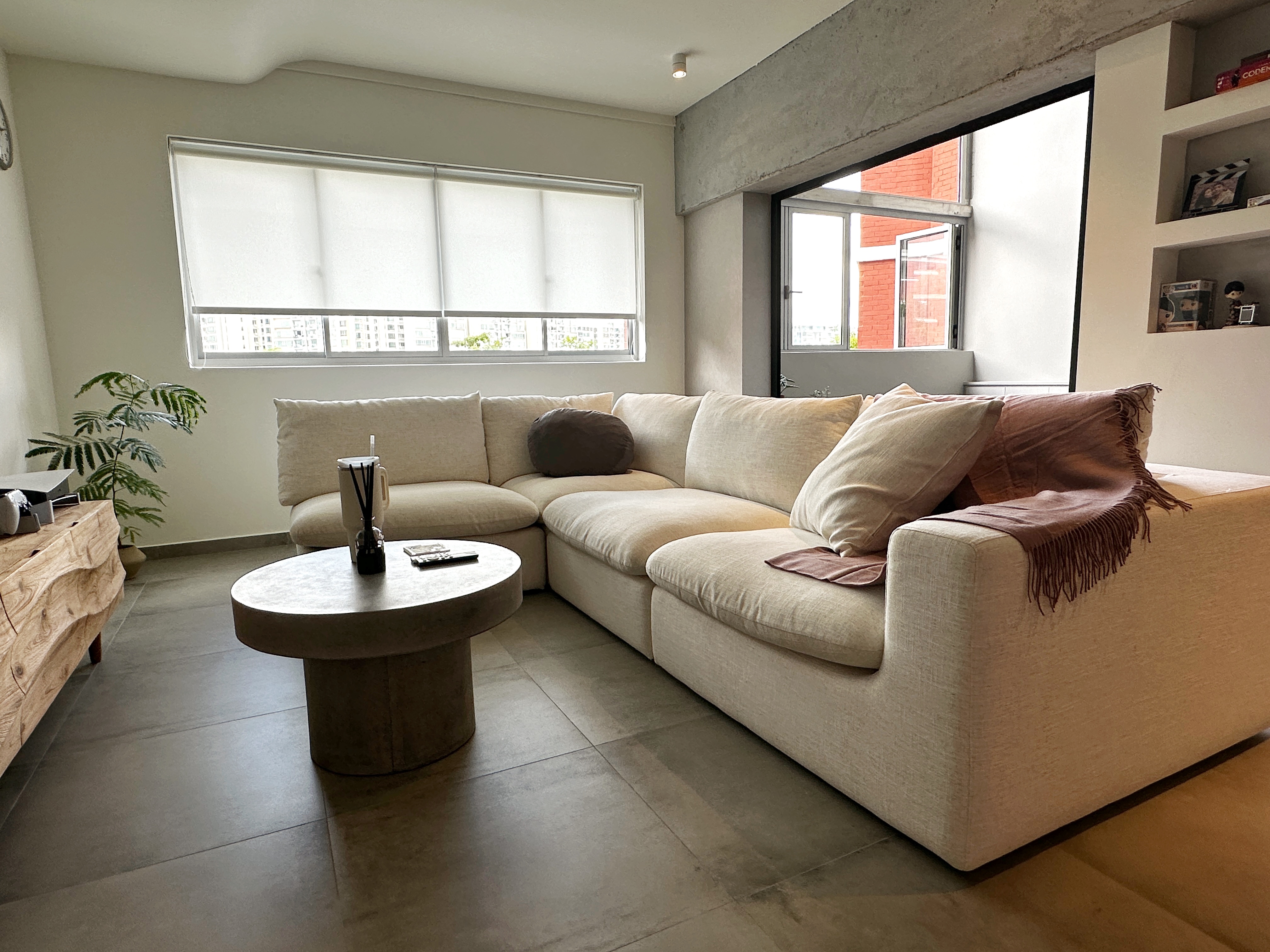 Mini Garden  - Modern living room with beige sectional sofa, large window with blinds, wooden coffee table, brown throw