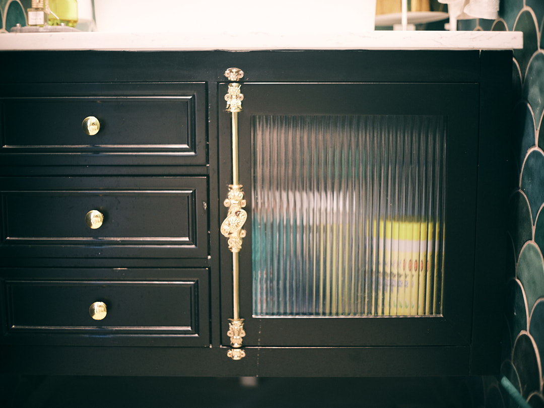 The Mermaid's Castle (Bathroom 1/3) - Dark wooden cabinet with brass handles, glass door, vertical blinds, green and white