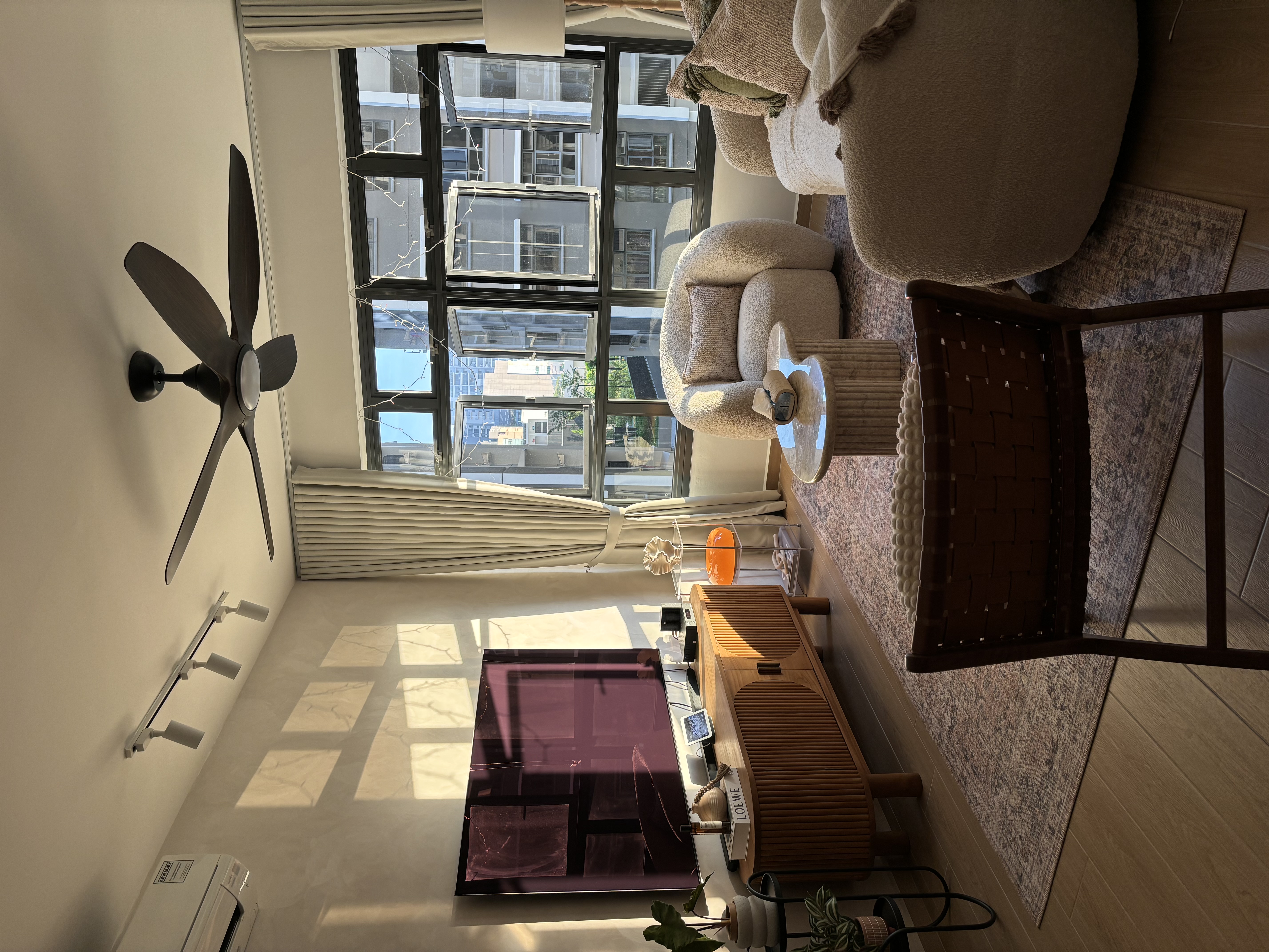 Our Simple & Cosy Living Room - Modern living room with large windows, beige sofa, coffee table, decorative rug, ceiling fan