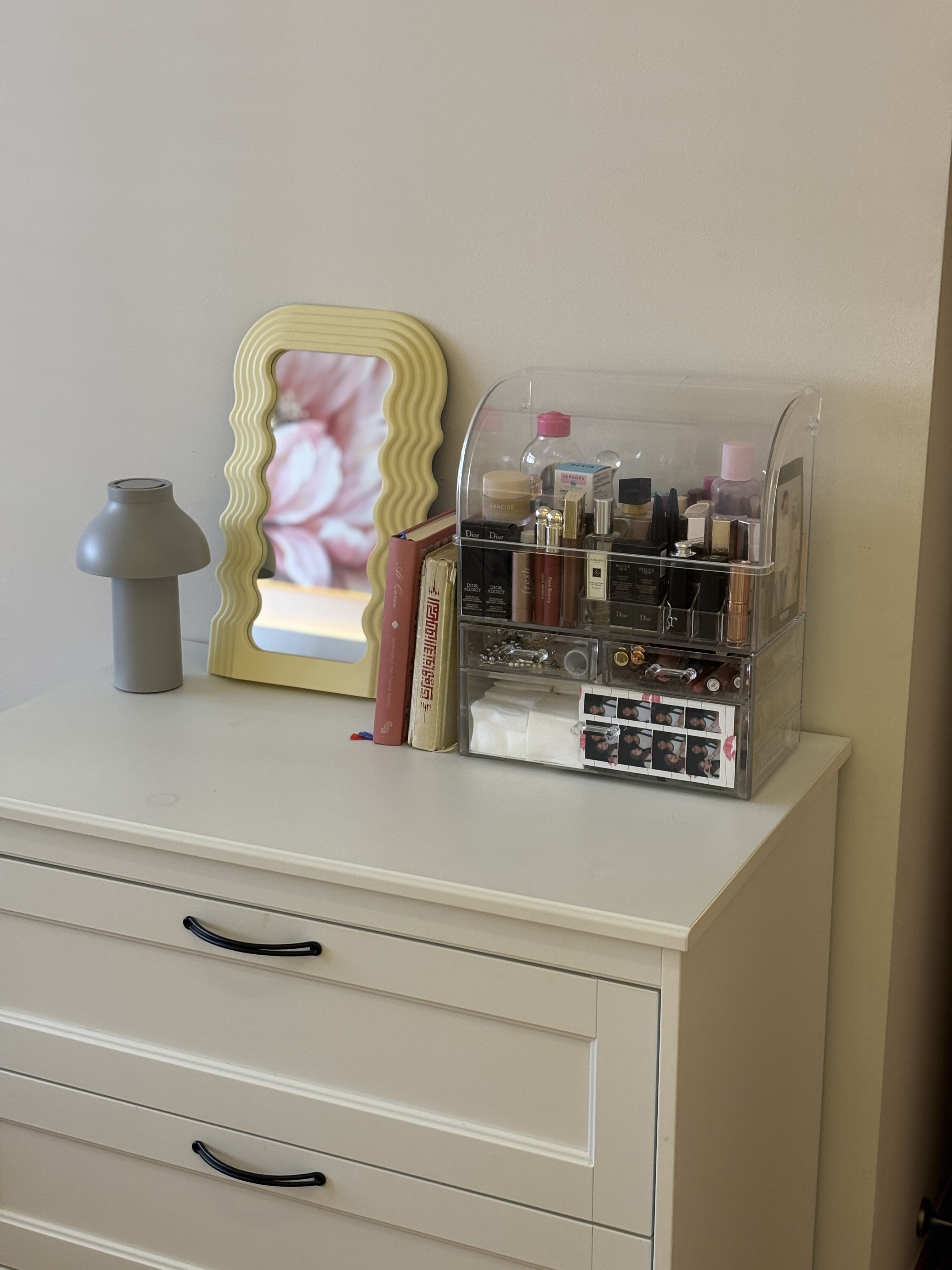 A peek inside our Master Bedroom - White vanity with gray lamp, yellow mirror with floral frame, clear makeup organizer