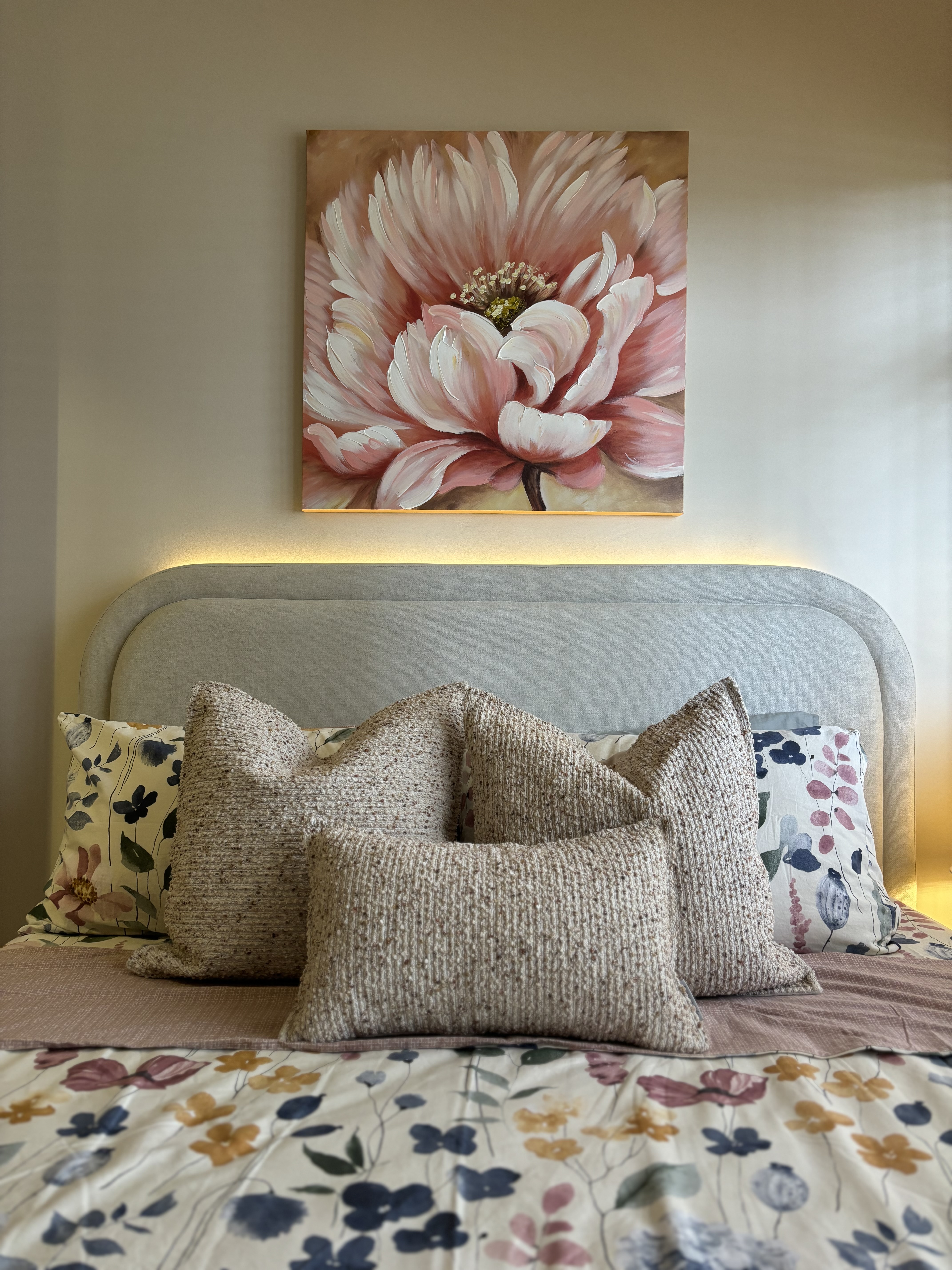 A peek inside our Master Bedroom - Floral-patterned pillows, floral bedspread, abstract painting, soft lighting, cozy