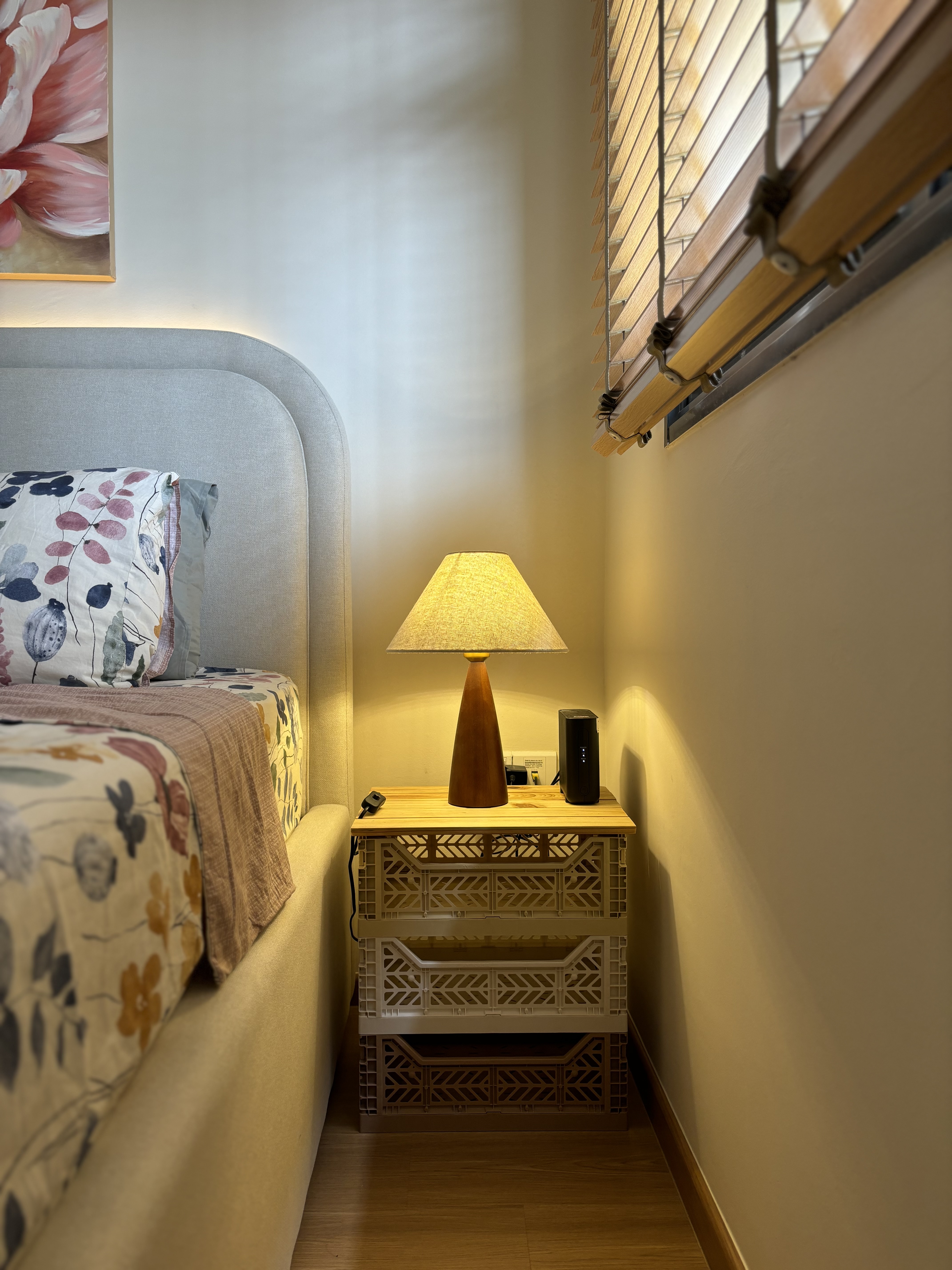 A peek inside our Master Bedroom - Floral-patterned bed sheets, wooden nightstand, modern lamp with beige shade, beige