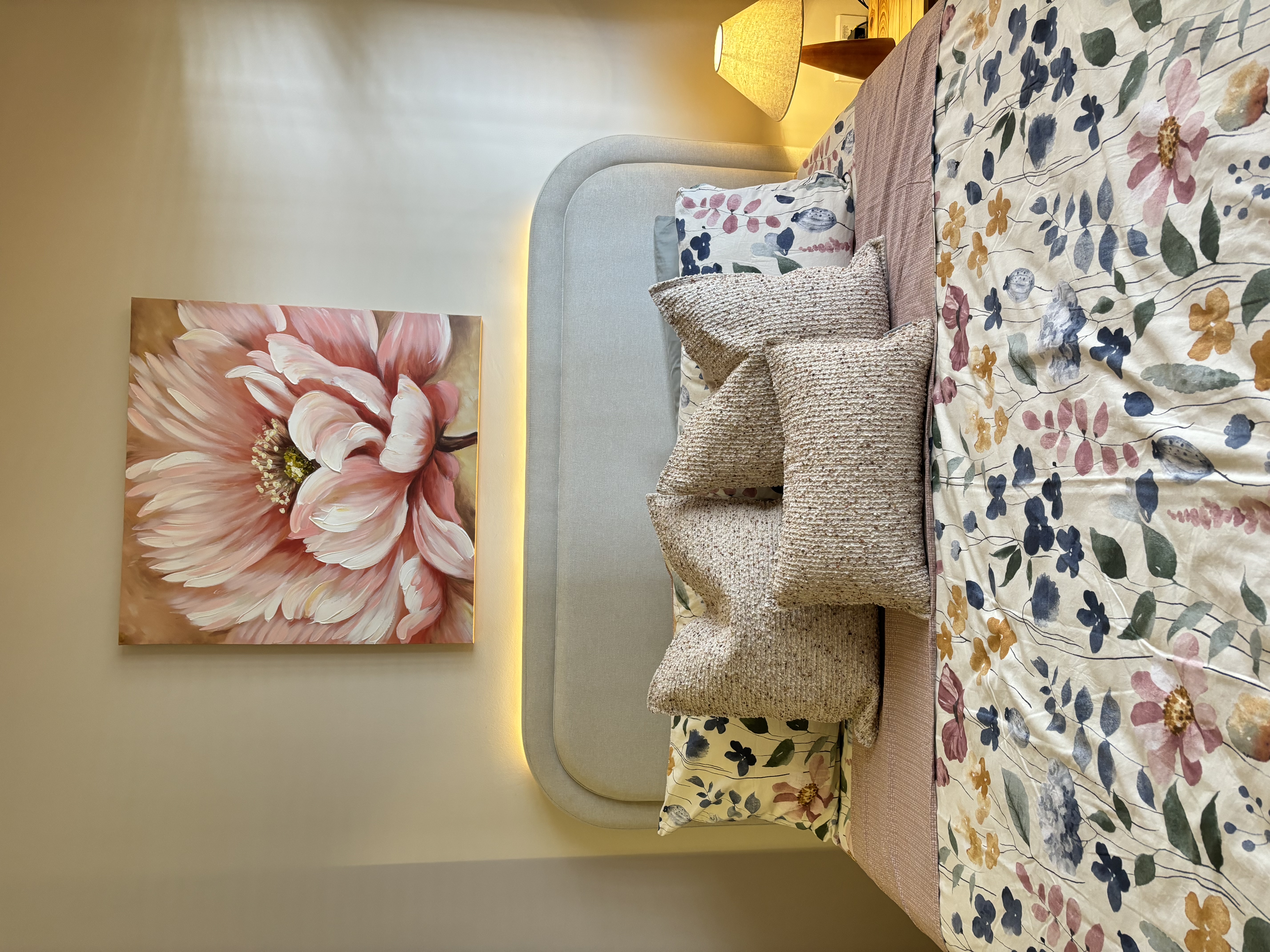 A peek inside our Master Bedroom - Floral-patterned pillows, floral print bedspread, cozy bedroom, soft lighting, pastel pink