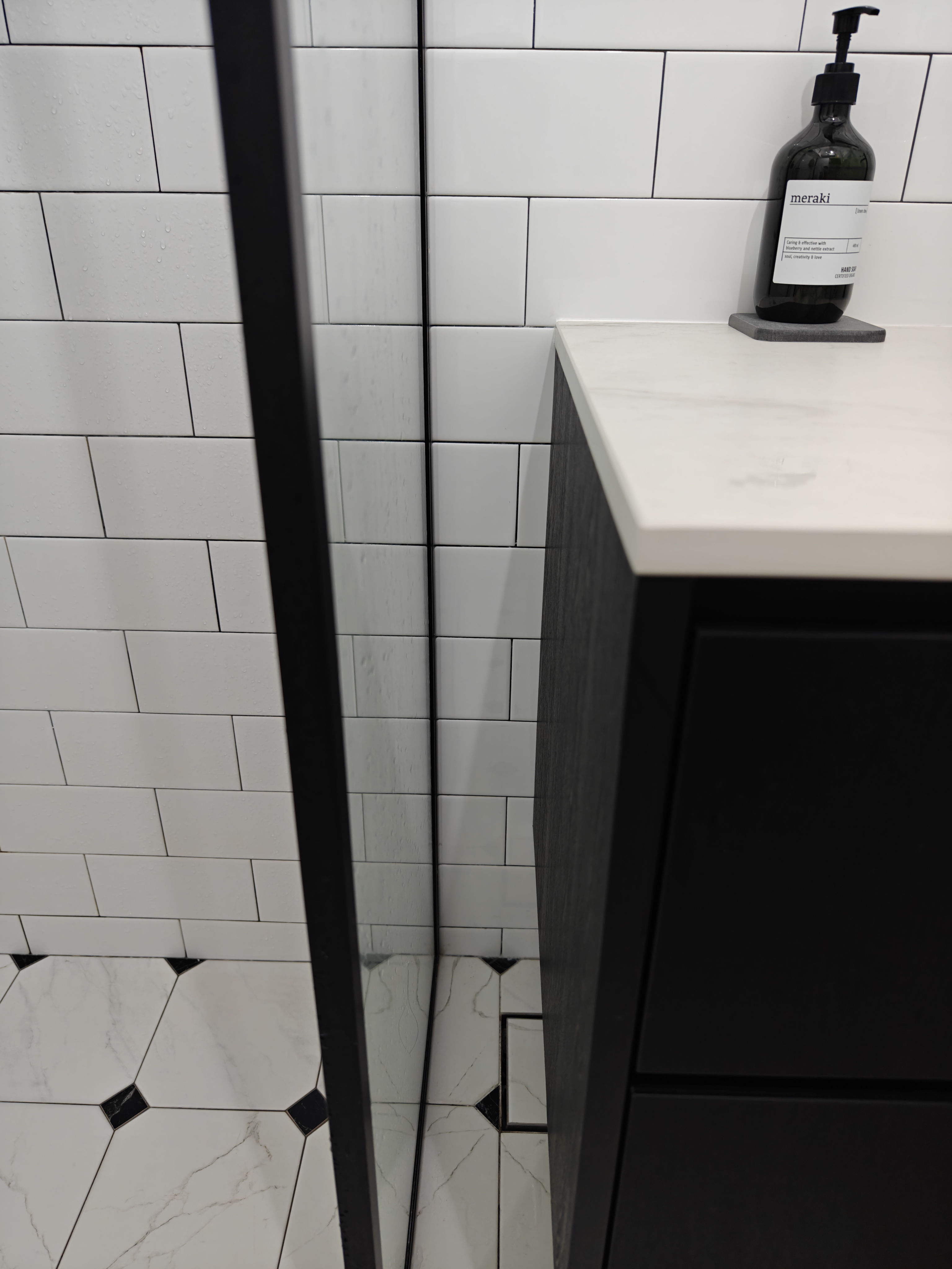 "Oh You Have 3 Bathrooms?!" - White tiled wall, black countertop, black soap dispenser, marble floor, black cabinet, white