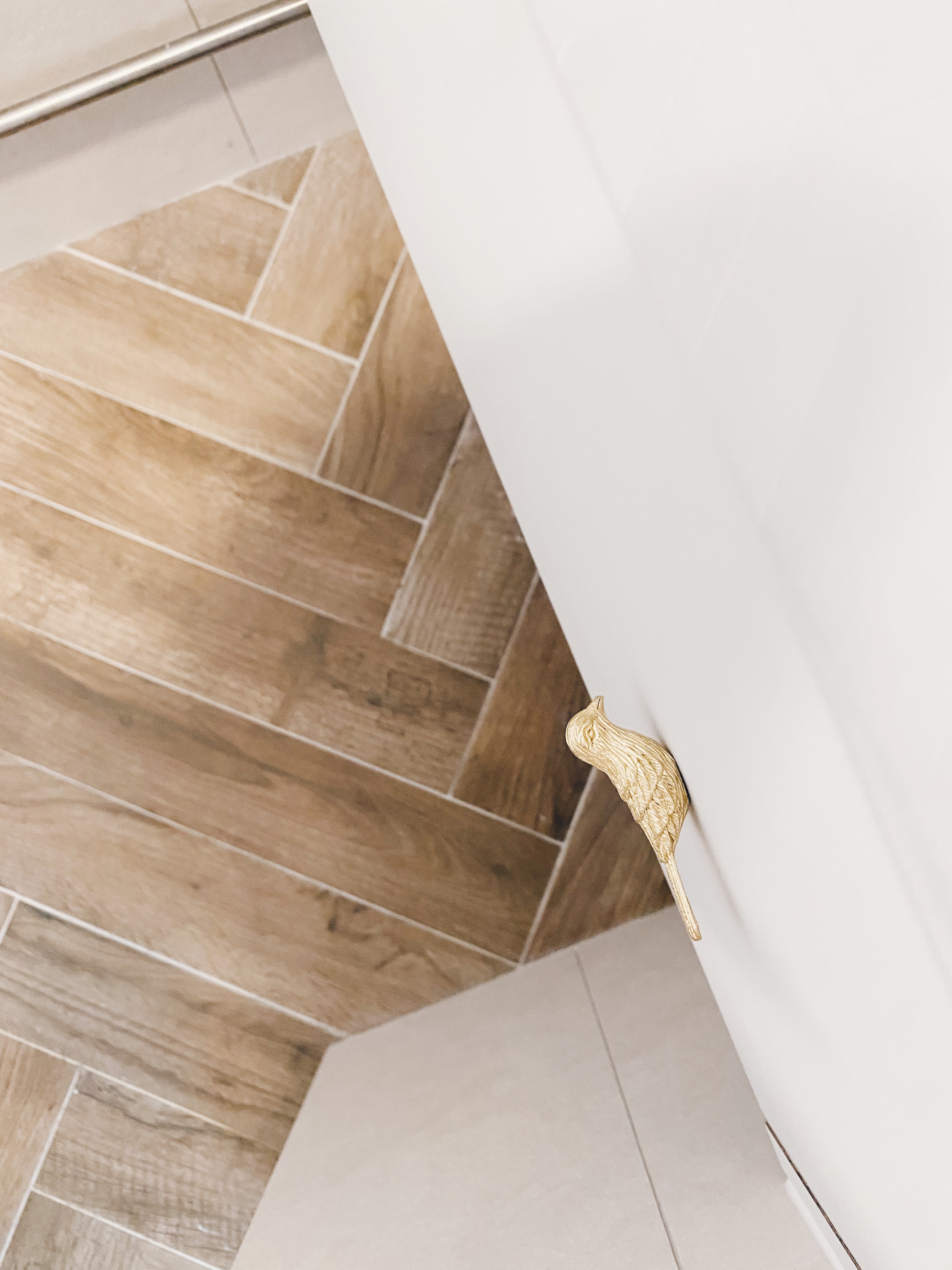 Our Bathrooms and their Personalities - Golden decorative animal paw, wooden herringbone tile floor, modern staircase corner