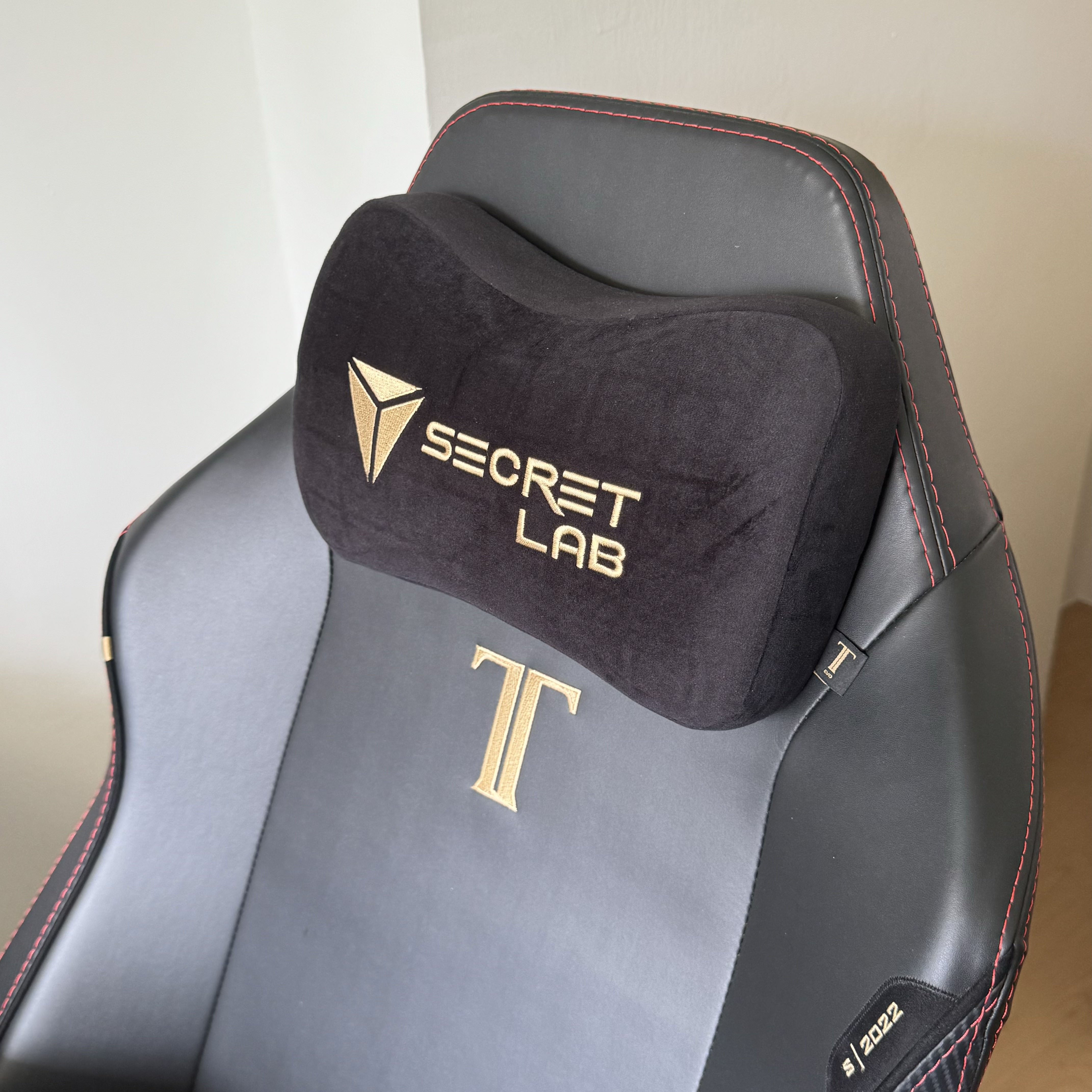 A tiny study room for the tiny tofus  - Black gaming chair with red stitching, gold "SECRET LAB" logo, gold "T" logo, gold "S