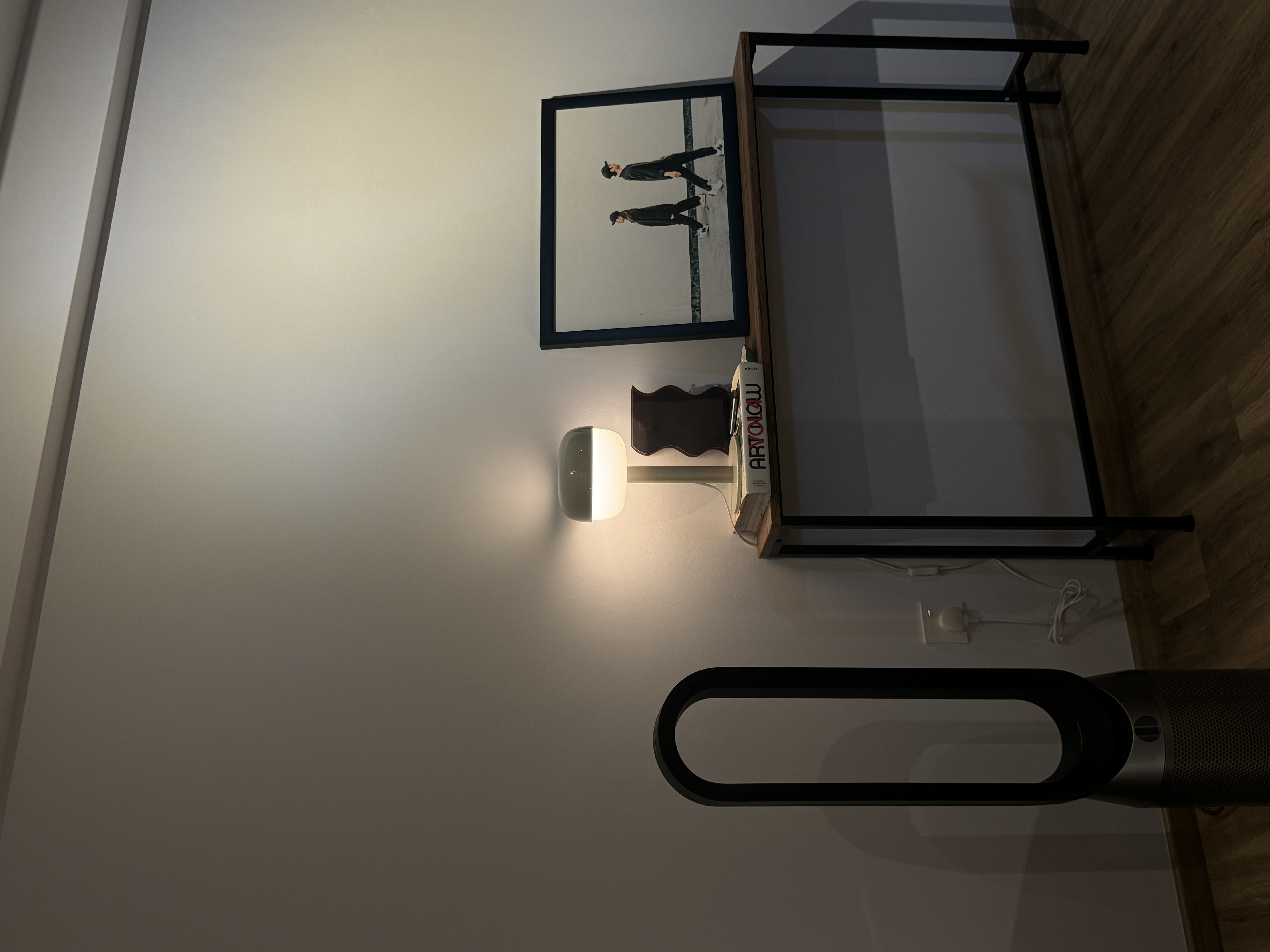 A characterful living room - Modern minimalist decor, sleek black shelf, framed picture, wooden floor, soft ambient light