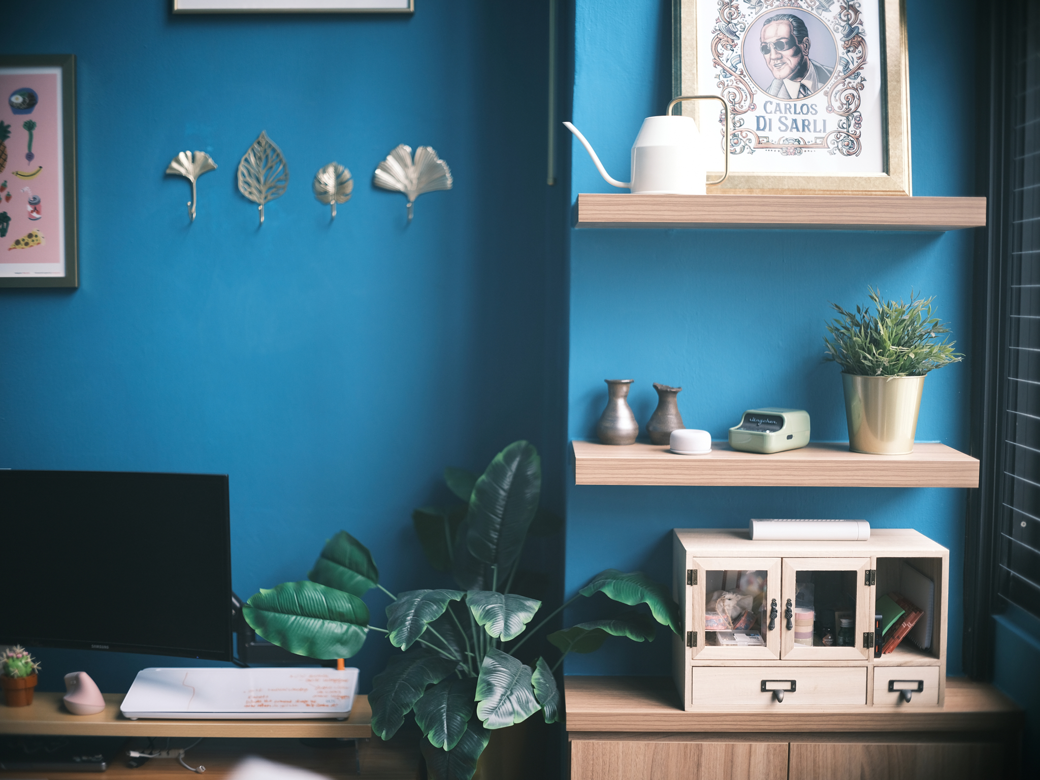 A chic turquoise study with dramatic double-volume windows - Blue wall, modern desk, framed portrait, white teapot, metallic