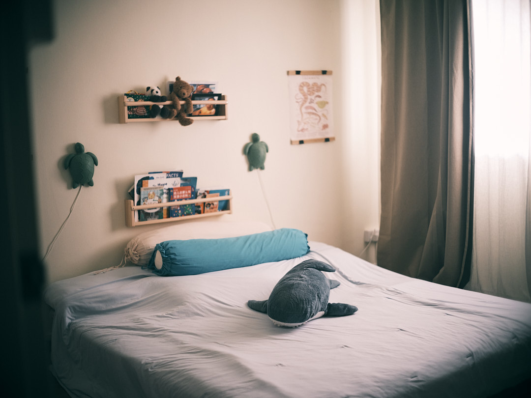 A charming bedroom for a golden childhood - Child-friendly bedroom with soft, natural light, plush blue pillow, neatly made
