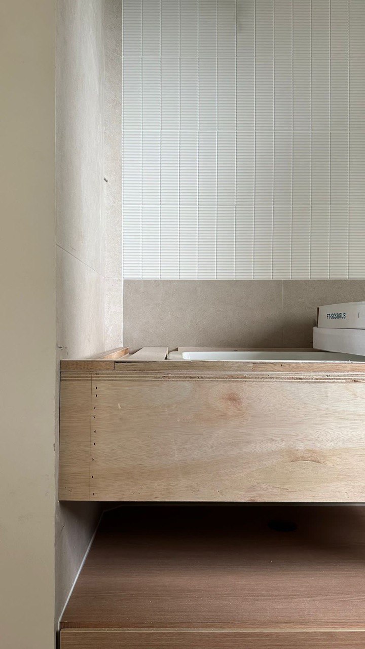 Bathroom: Creating textures through tiles - Wooden vanity with integrated sink, light beige wall tiles, minimalist design