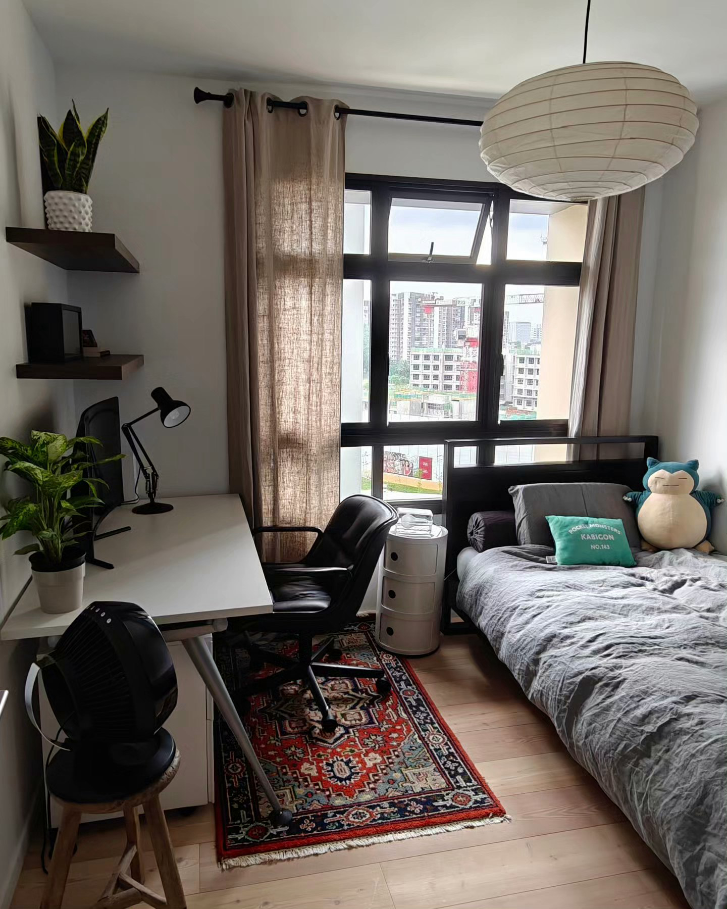 You Light Up My Life! - Modern bedroom with large window, beige curtains, wooden floor, colorful rug, black office chair
