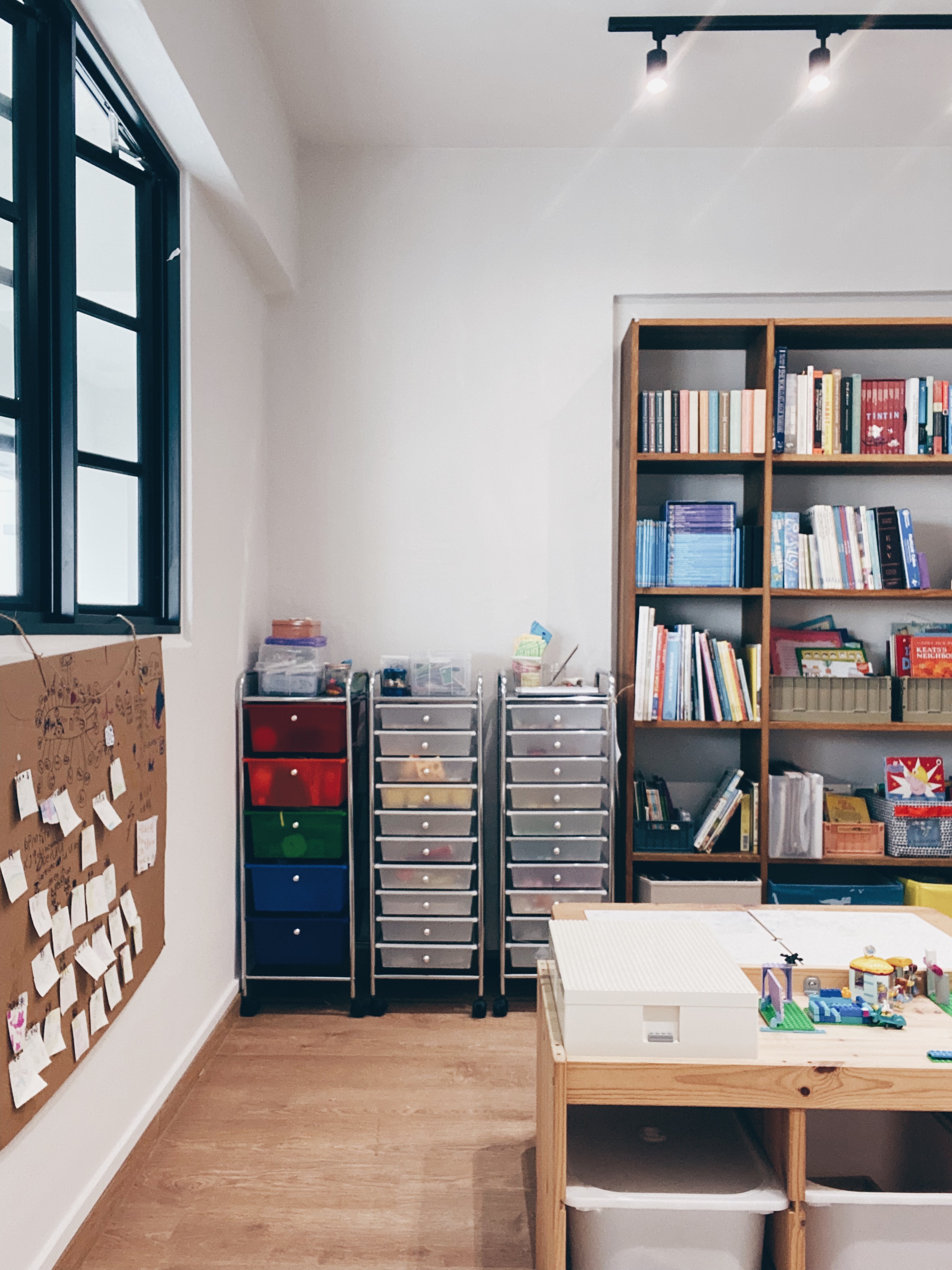 Cohabiting: working and playing together - Wooden floor, bookshelf, colorful drawers, bulletin board, children's artwork