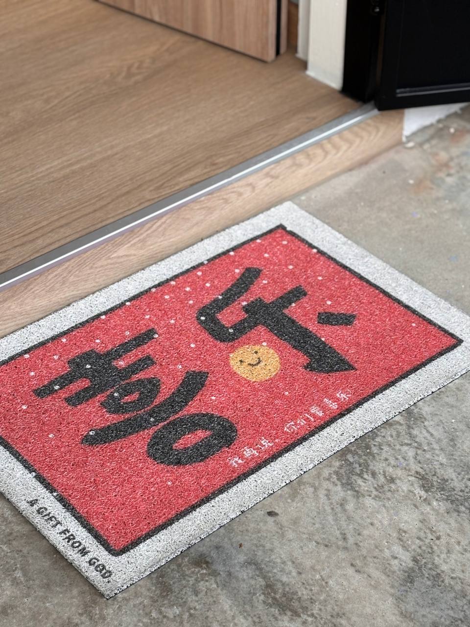 Top 3 Things for an Entryway - Red and black doormat with Chinese characters and a smiley face, wooden floor, concrete