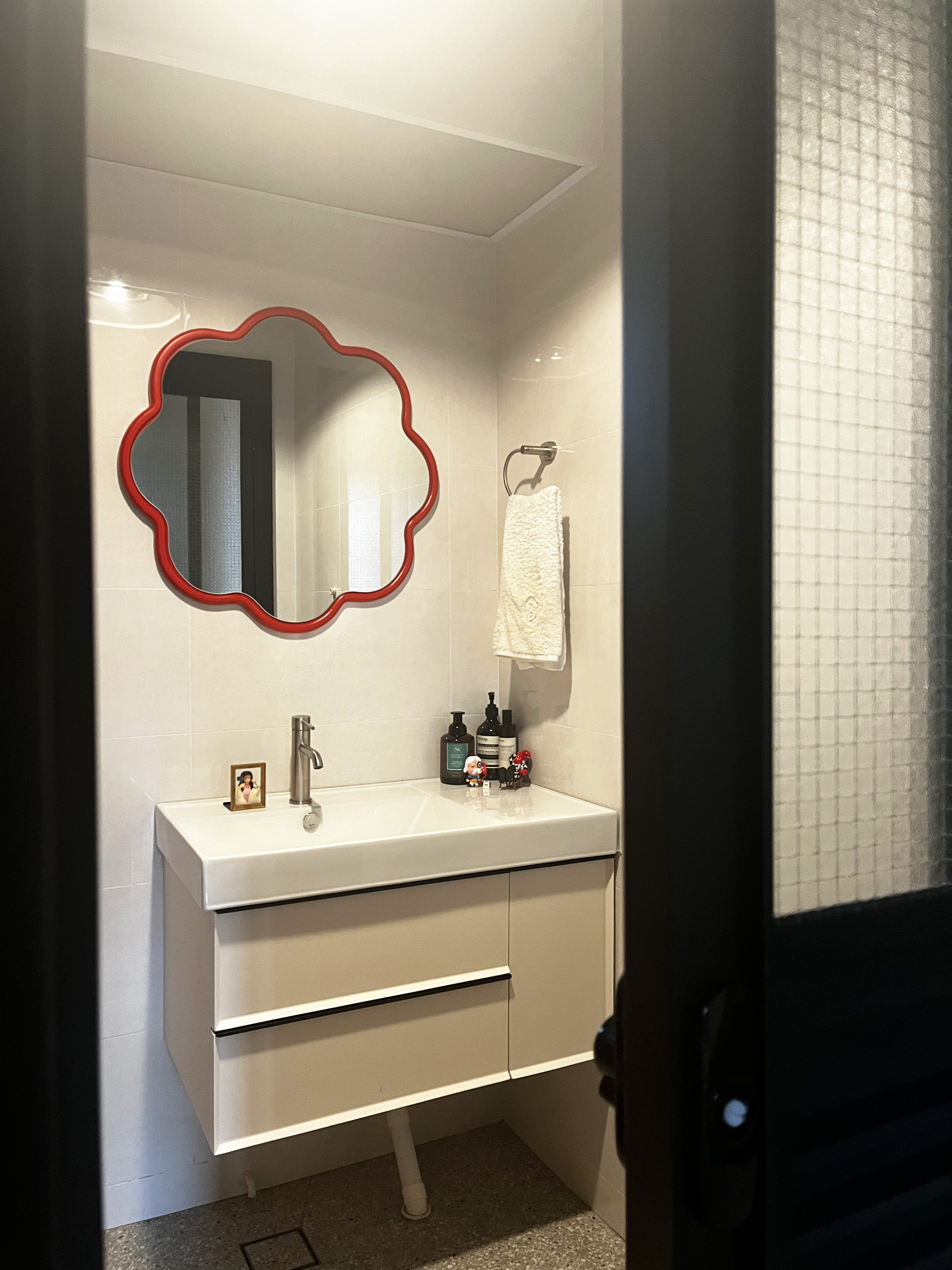 Into the room of the porcelain throne🚽🧻 - White bathroom vanity, red oval mirror, white sink, small framed photo, black