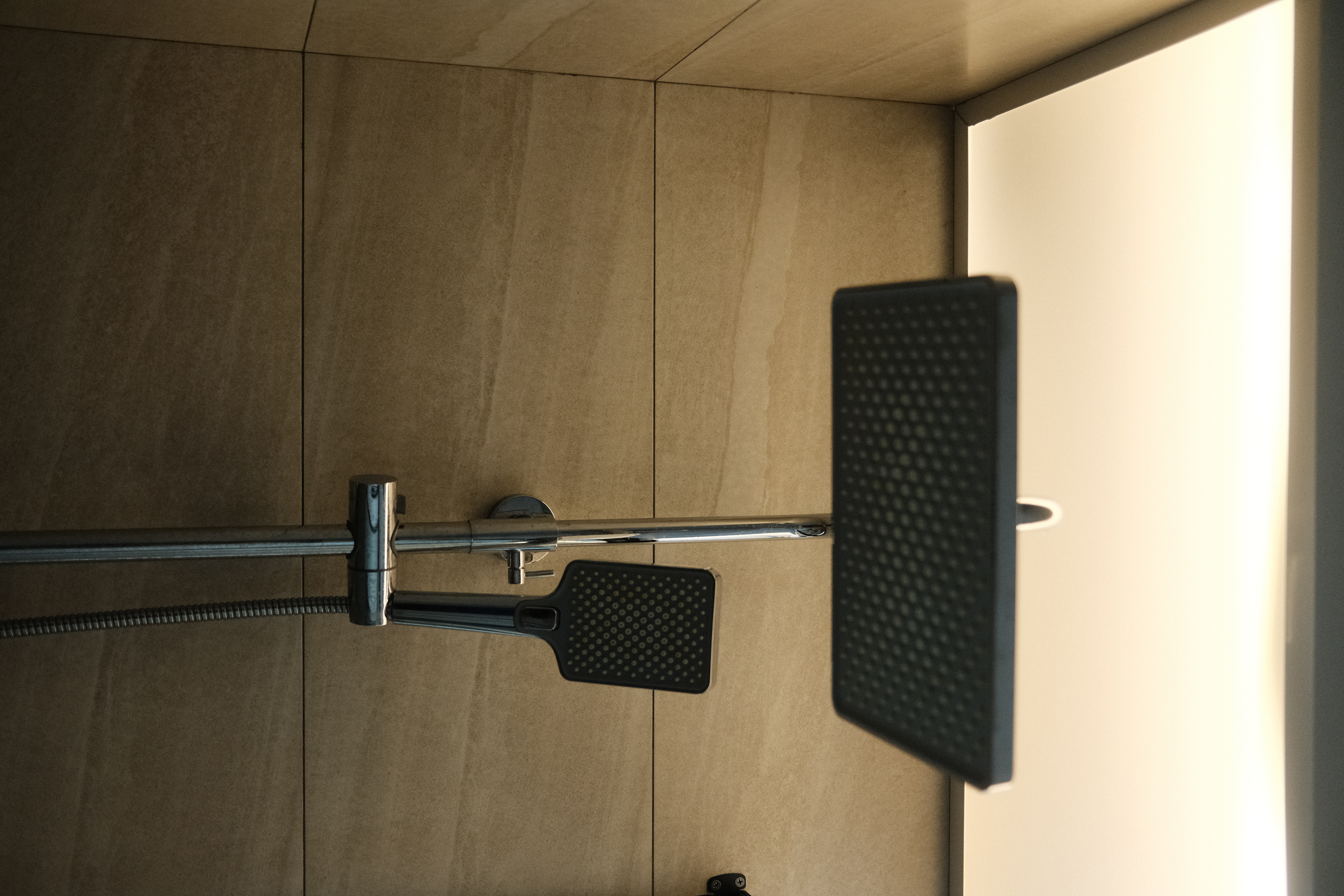 Balancing cost with aesthetics in our bathrooms  - modern bathroom, tiled wall, metallic shower fixture, black handheld