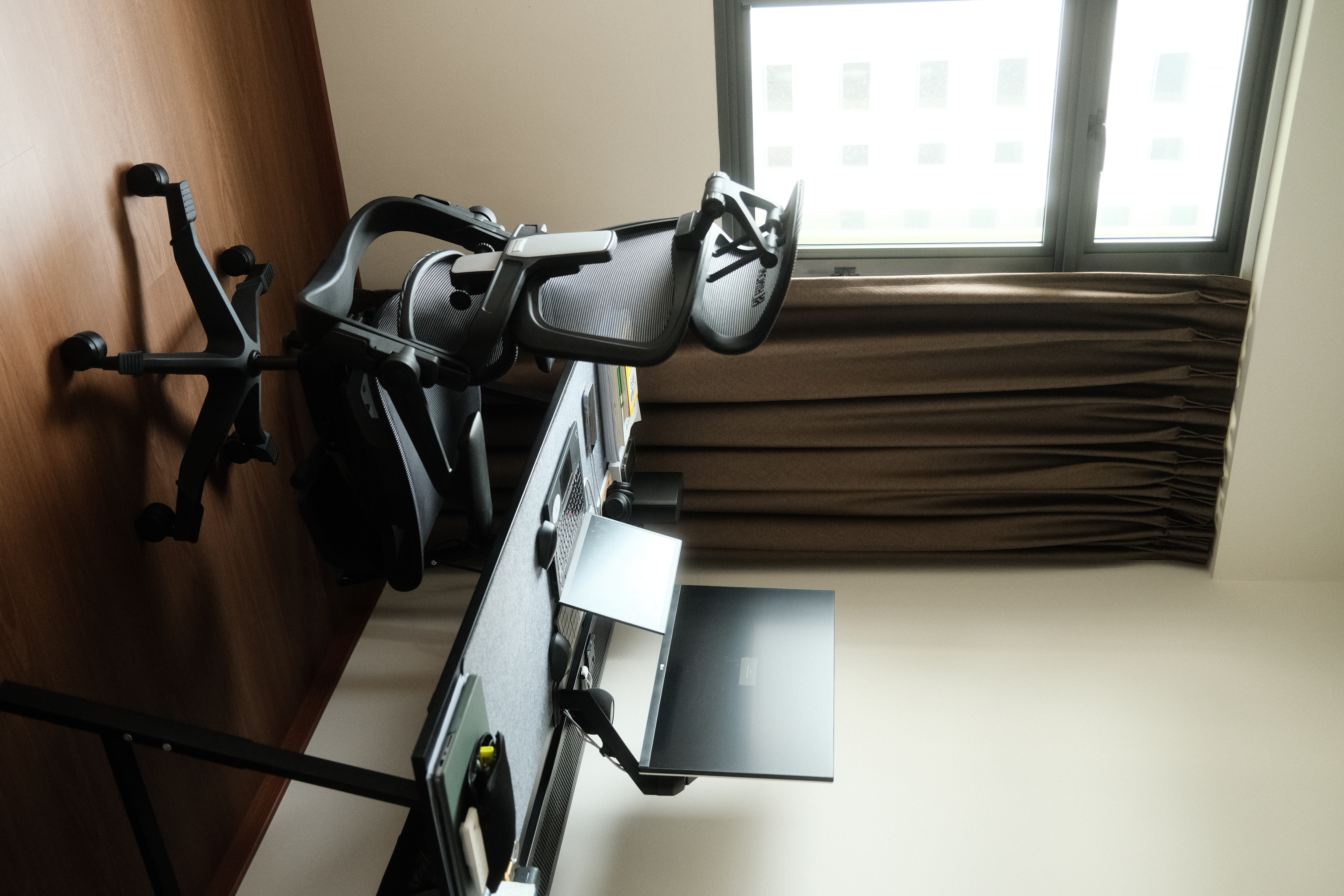 Our simple and minimal workspace - Desk with ergonomic chair, black office chair with wheels, brown curtains, window with