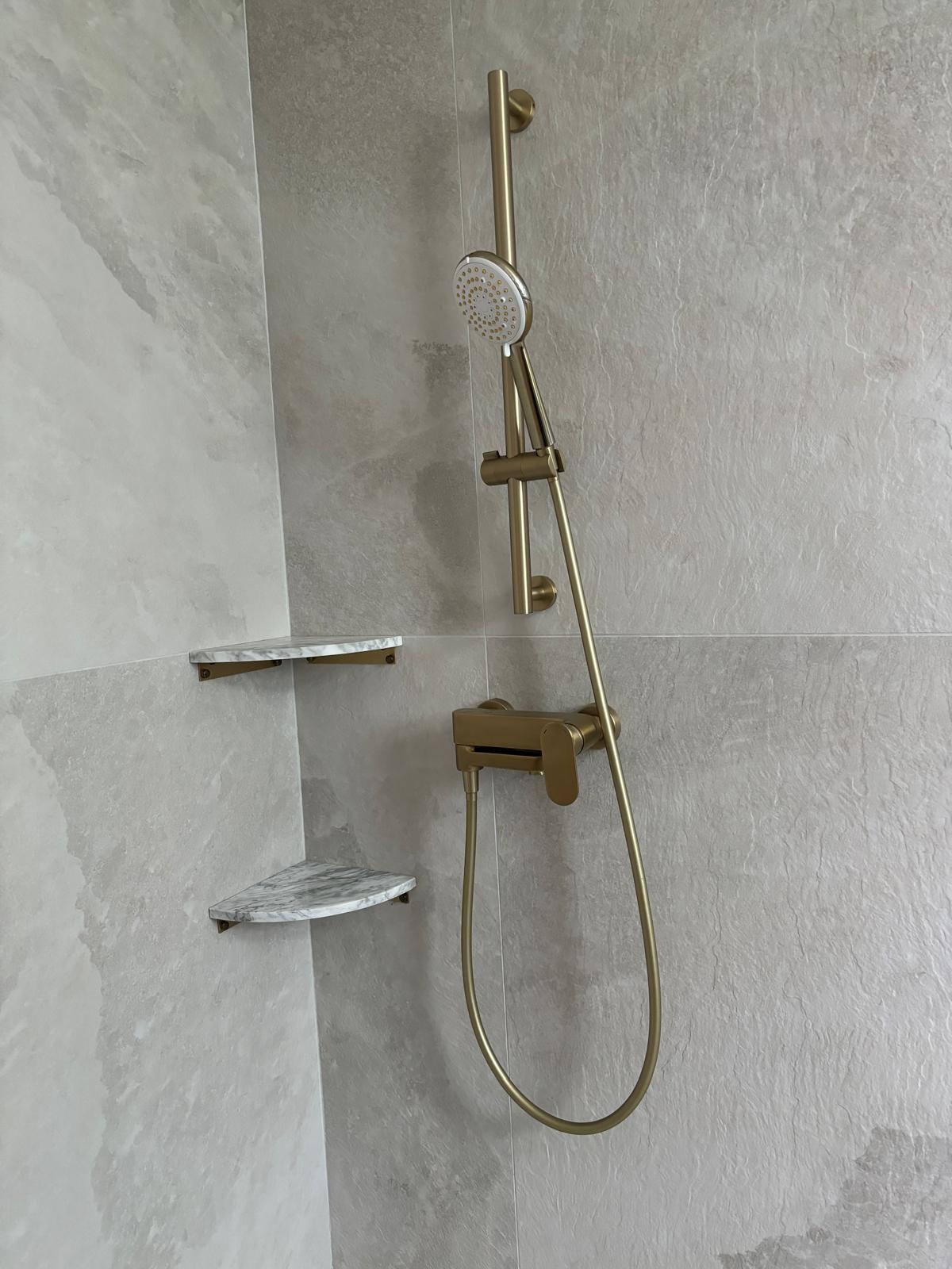 Black and white bathroom with lots of natural lighting  - gold shower head, marble wall, modern shower, brass fixtures