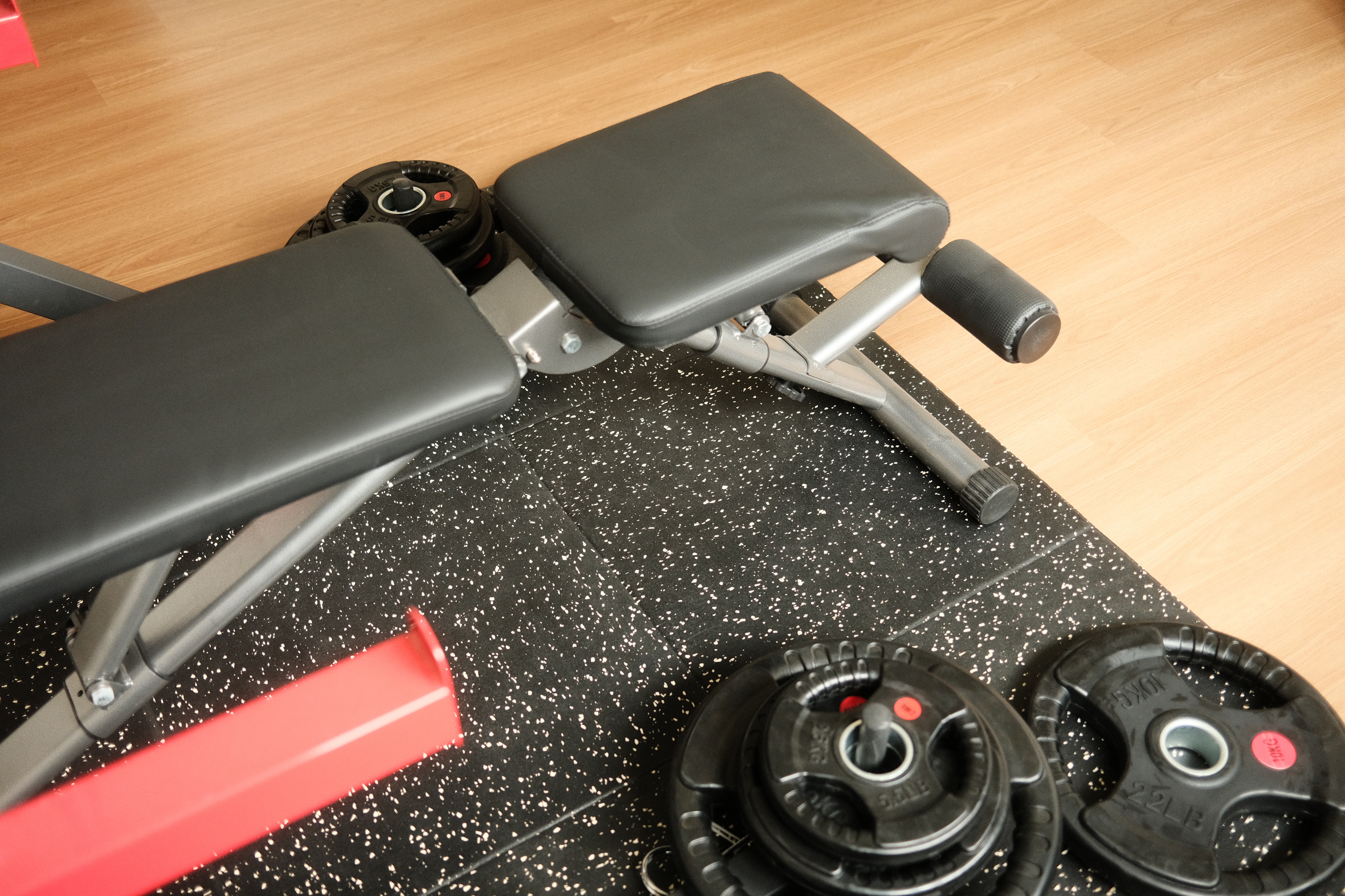 Trying to be healthy in our home gym - Black exercise bench, black cushioned seat, black rubber footrests, black weight