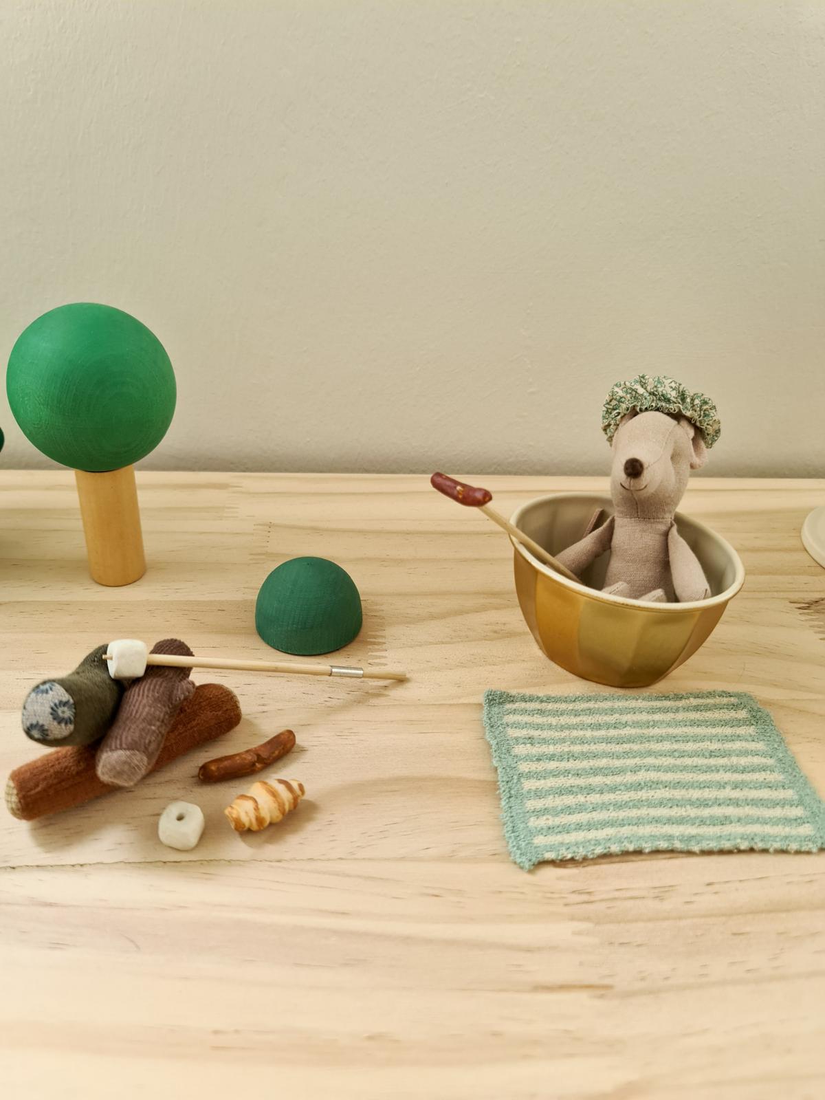 A safari themed kid's room  - Soft toy bear with green hat, wooden stick, green ball, brown stick, croissant, striped towel