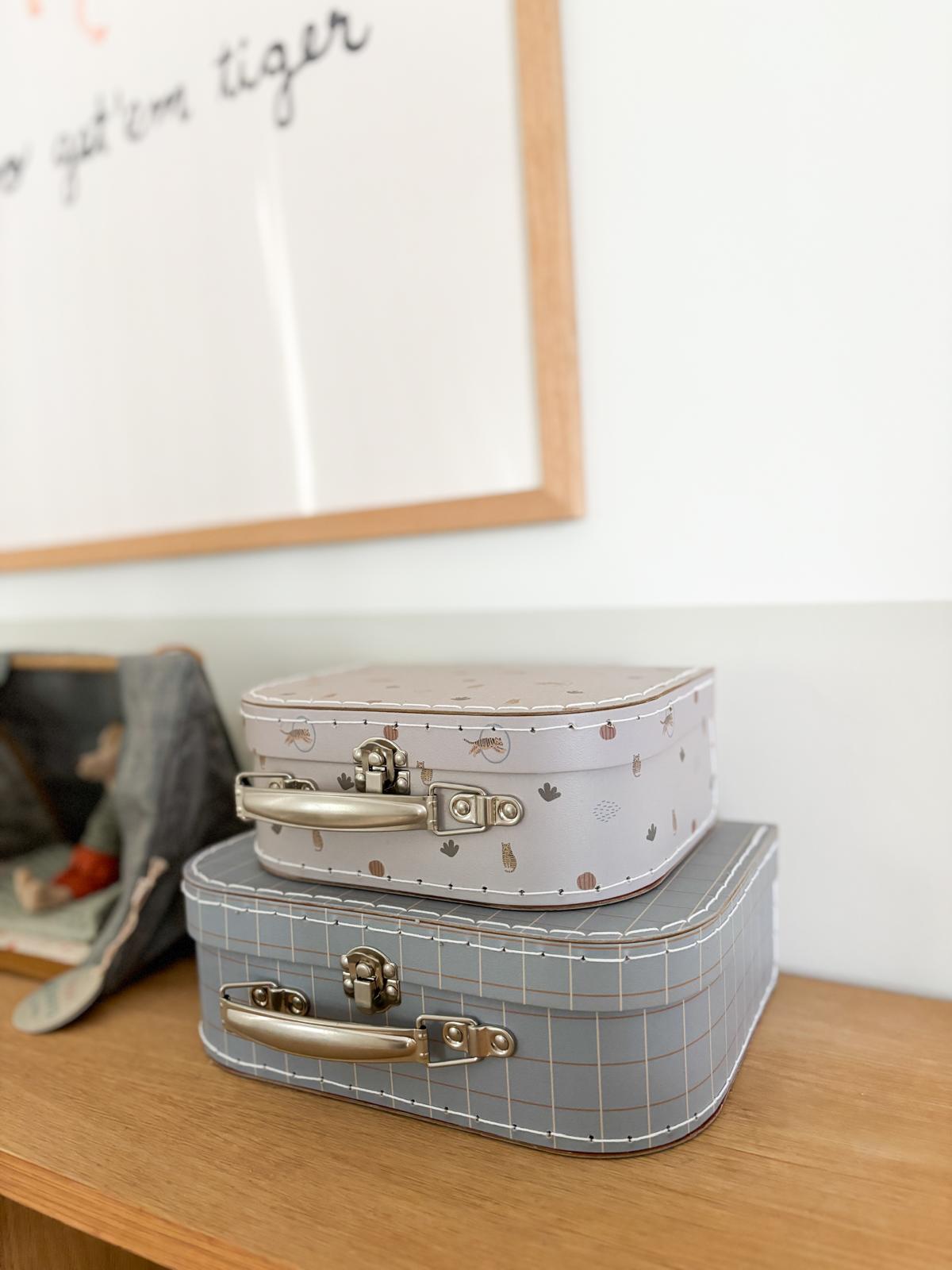 A safari themed kid's room  - Wooden table with two vintage-style suitcases, Light-colored suitcases with intricate designs