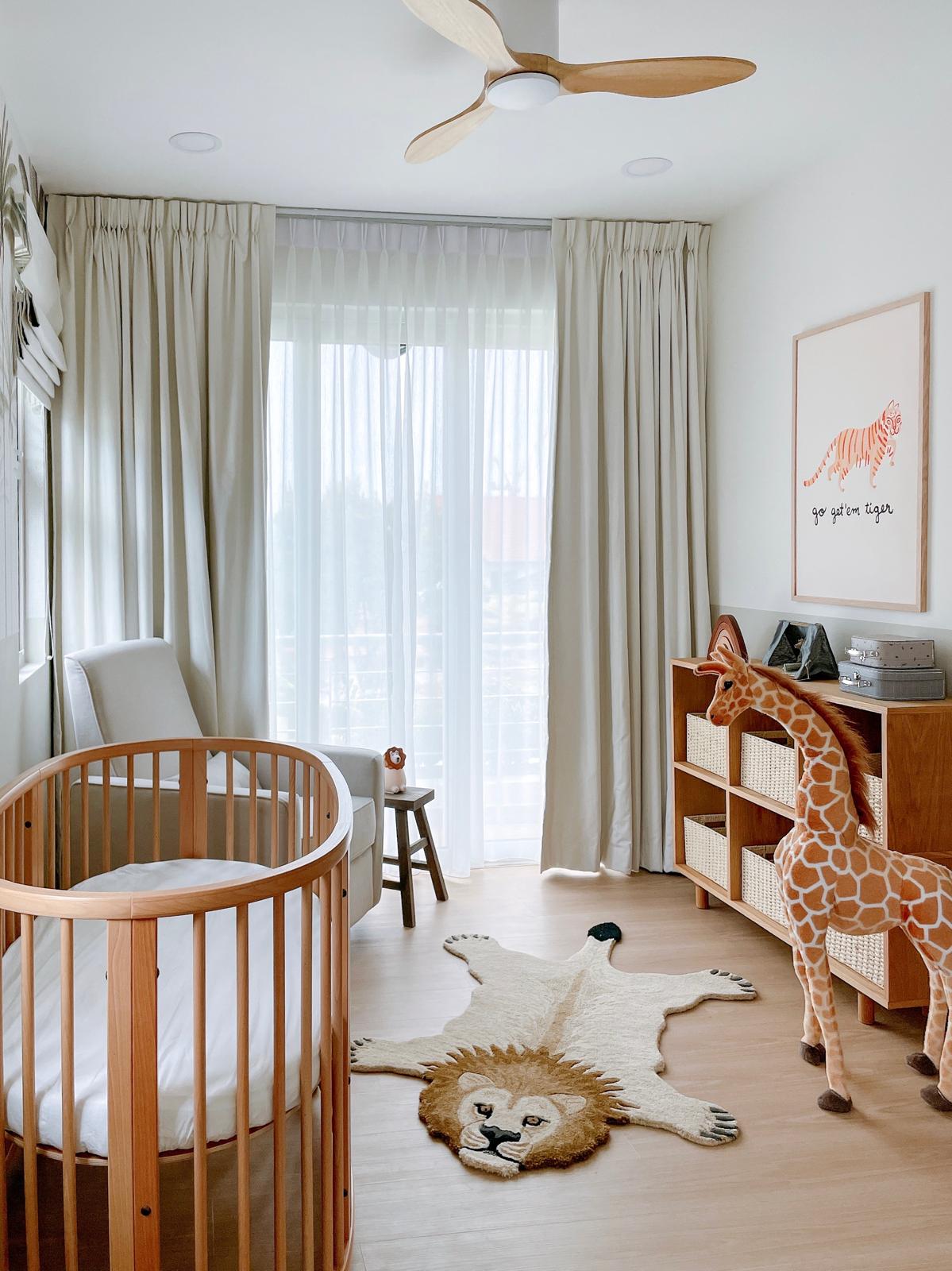 A safari themed kid's room  - Wooden crib, baby swing, wooden furniture, beige curtains, white walls, floor-to-ceiling