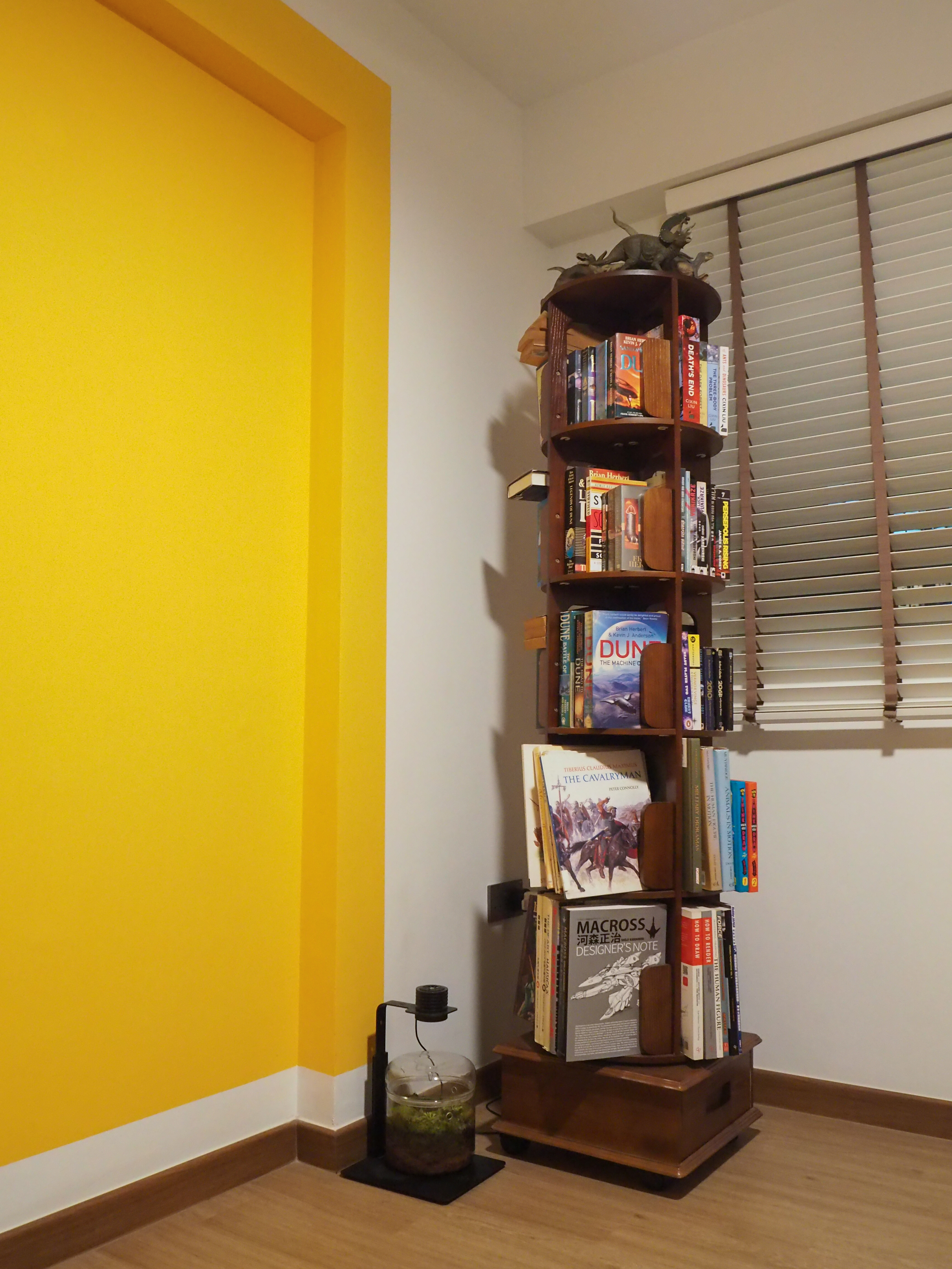 Our Workspace with zero built-in + pops of colours - Yellow wall, wooden bookshelf, books on shelves, dragon figurine, "Dune"