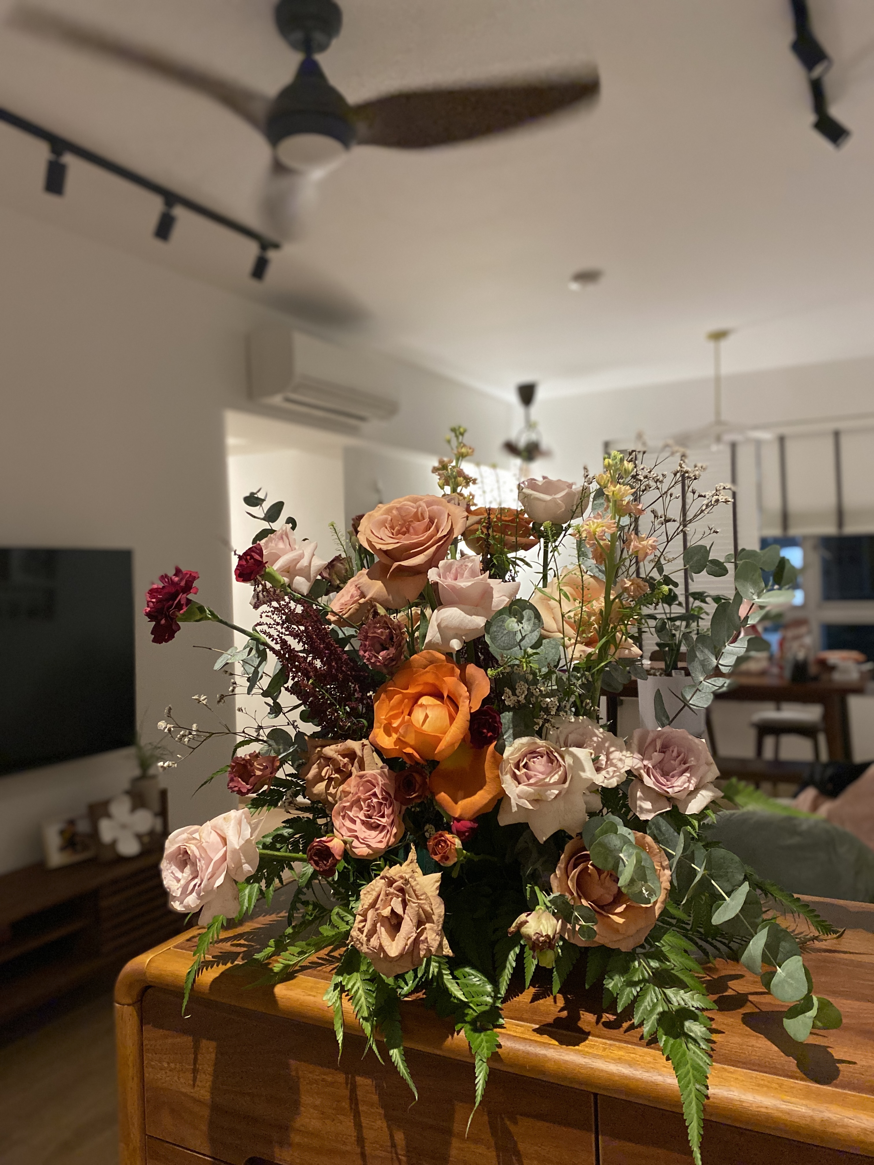 Our no frills entryway - vivid bouquet of roses in warm tones, including peach, pink, and orange, with green foliage, placed