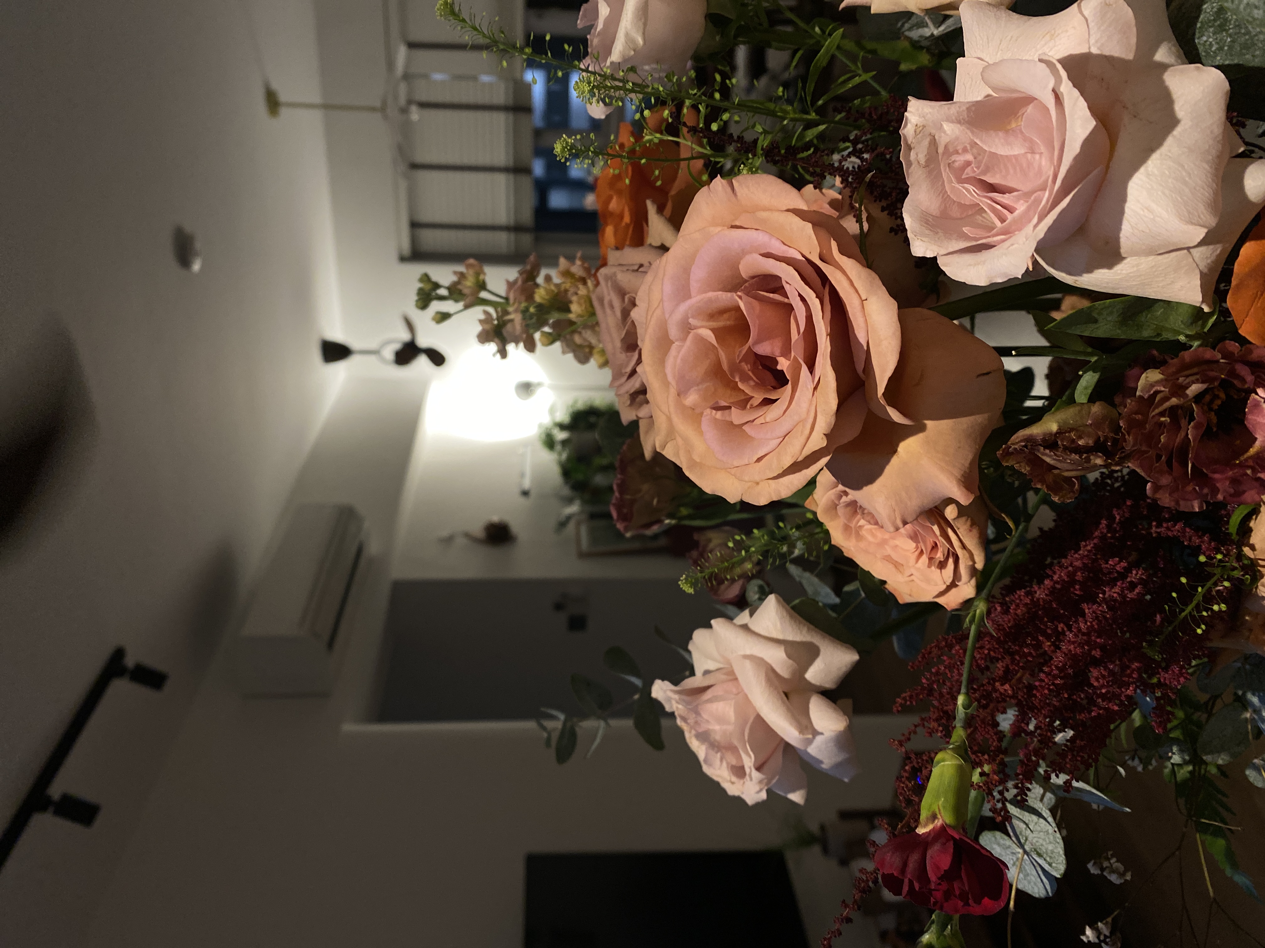 Our no frills entryway - Soft pastel roses, warm lighting, indoor setting, elegant arrangement, delicate petals, lush green