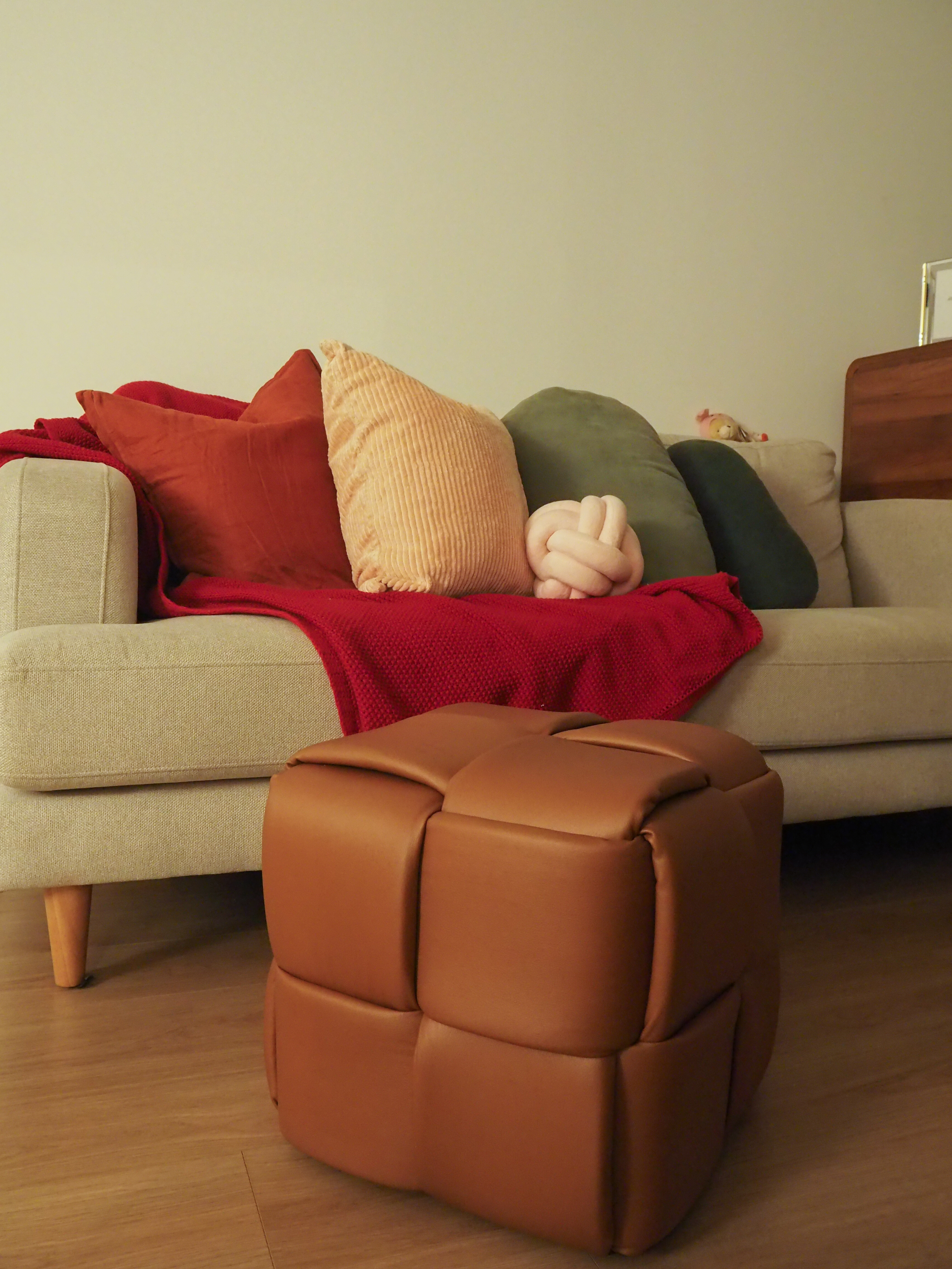 Favourite Cosy Corners  - Cream sofa, red blanket, beige cushions, plush toy, wooden legs, brown ottoman, soft cushions