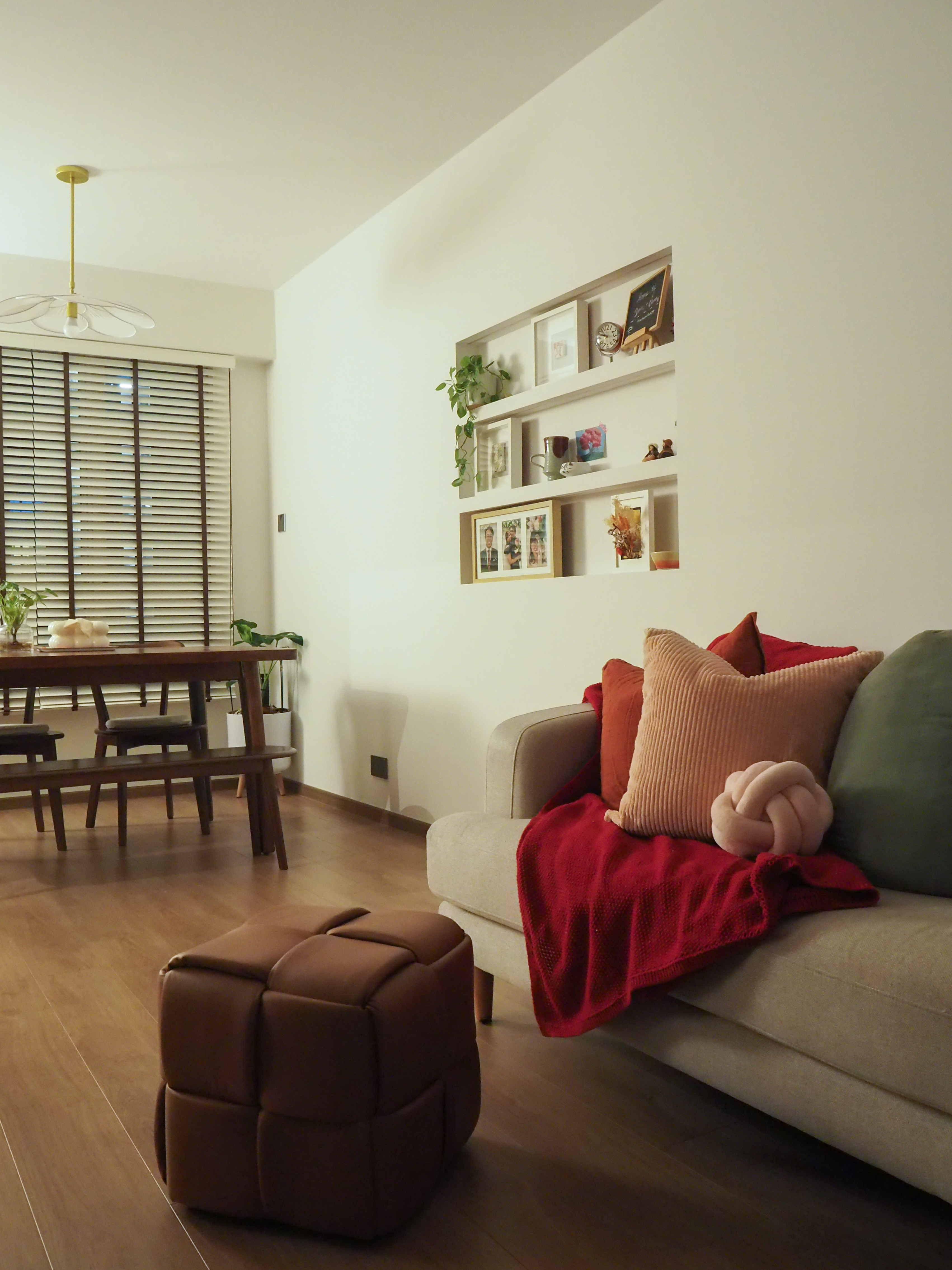Favourite Cosy Corners  - Modern living room with wooden floor, beige sofa, red throw blanket, green pillow, brown ottoman