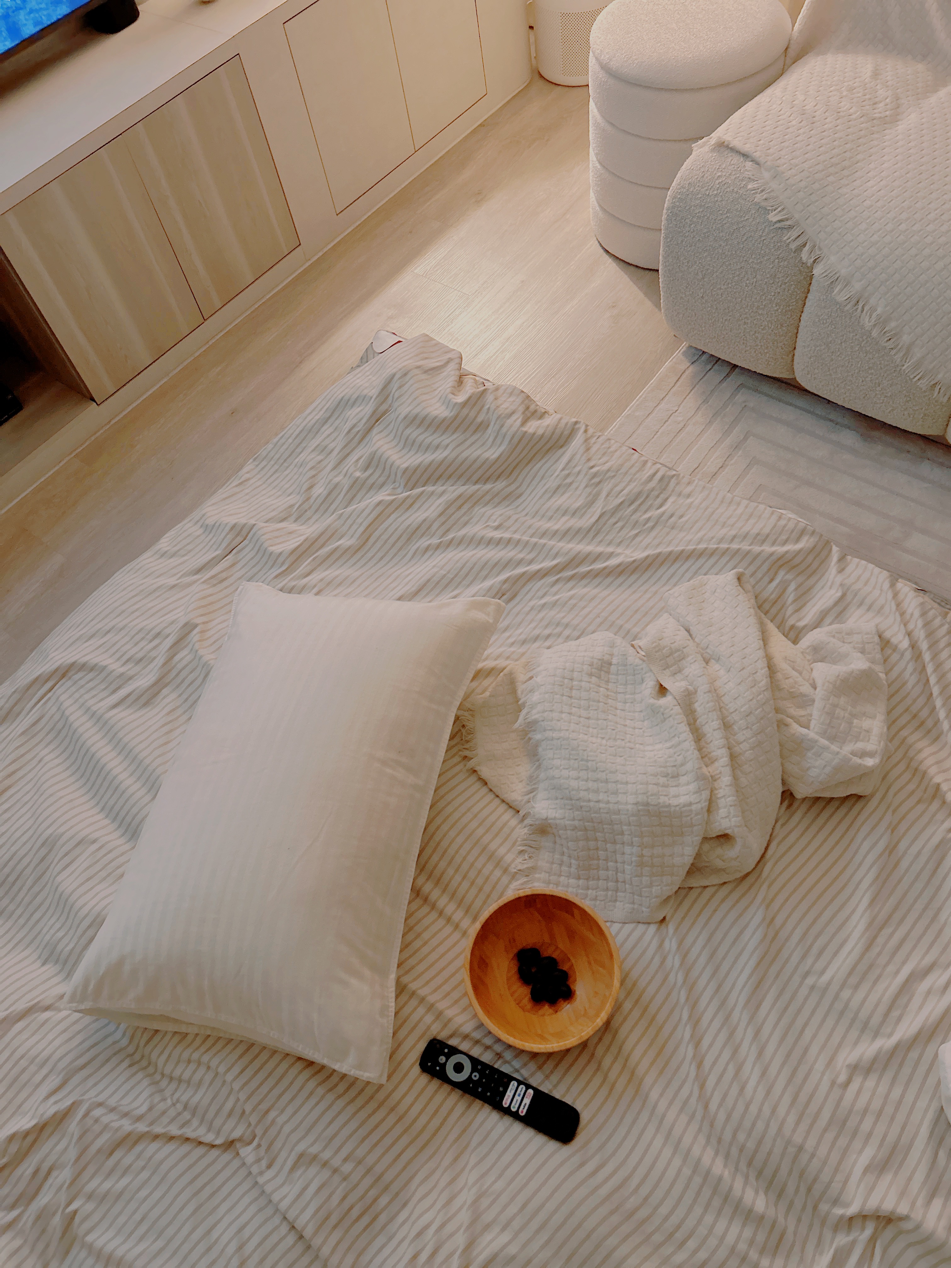 Guess our Favourite Spot to chill? - striped bedding, white pillows, wooden bowl, remote control, beige striped sheets, cozy