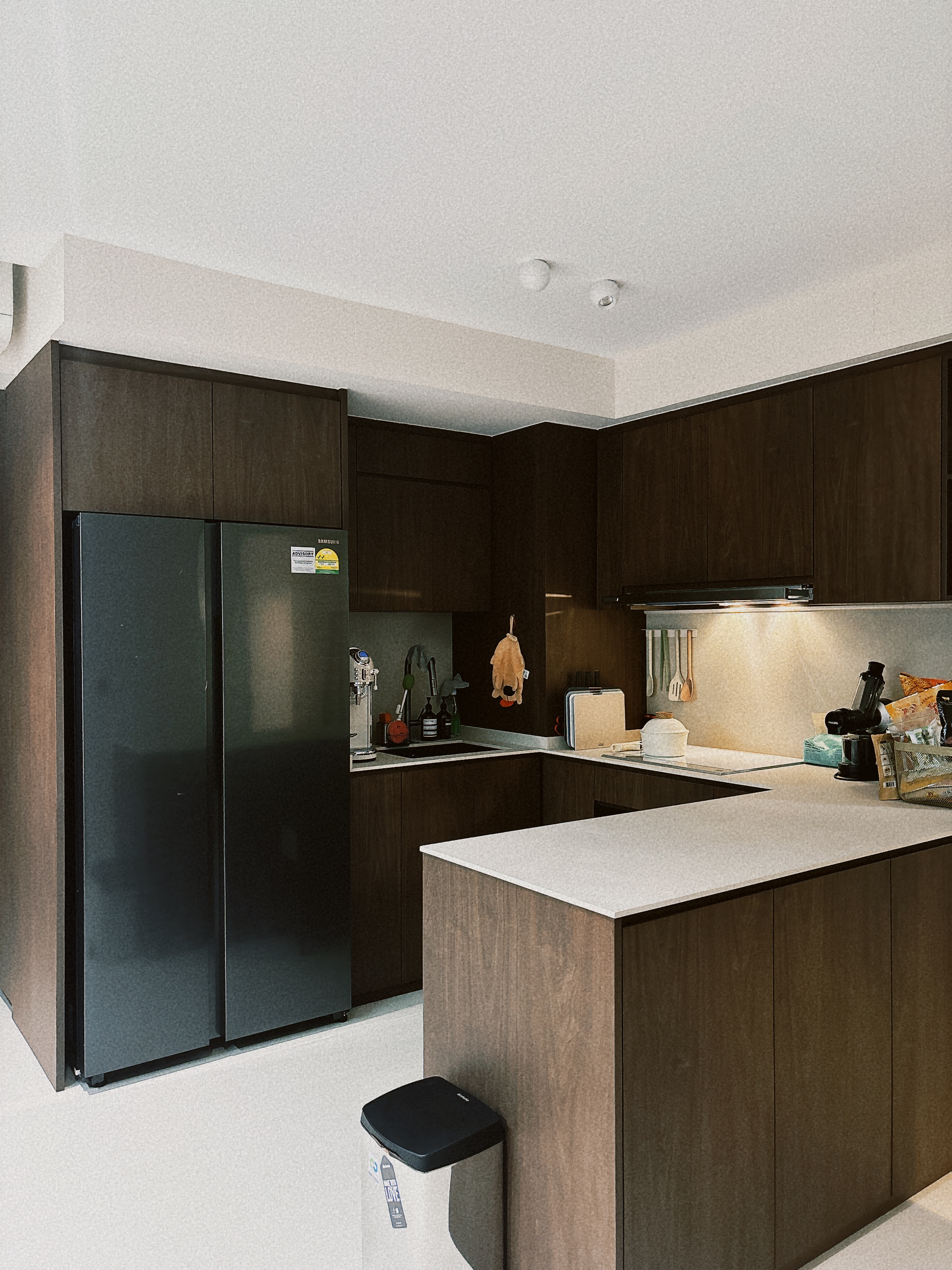 Our six-tile kitchen  - Dark wooden cabinets, sleek refrigerator, modern kitchen, light countertops, stainless steel sink