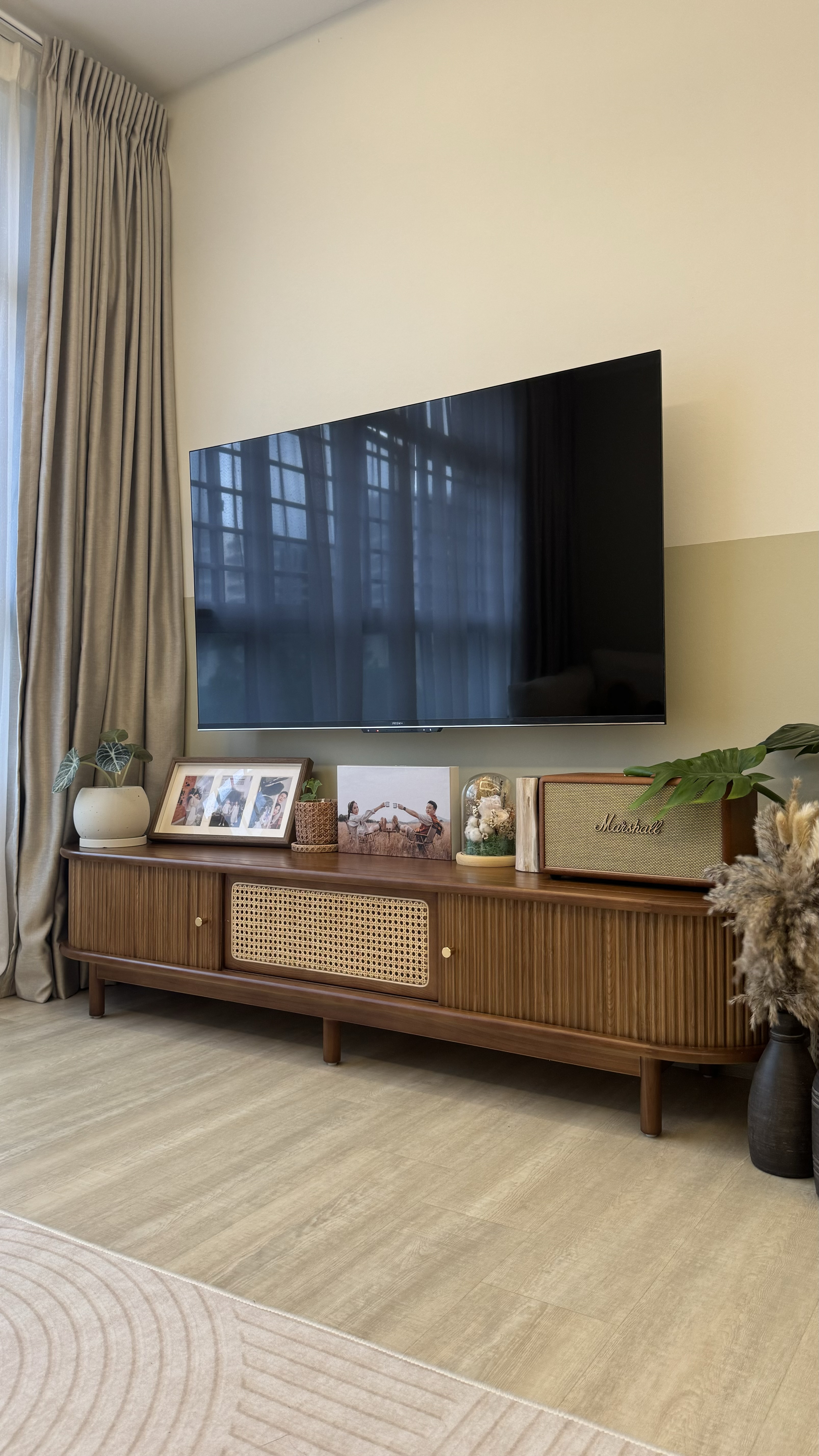 Our Secrets to Cable-Free TV Setup 📺  - Large flat-screen TV, beige curtains, wooden entertainment center, framed photos