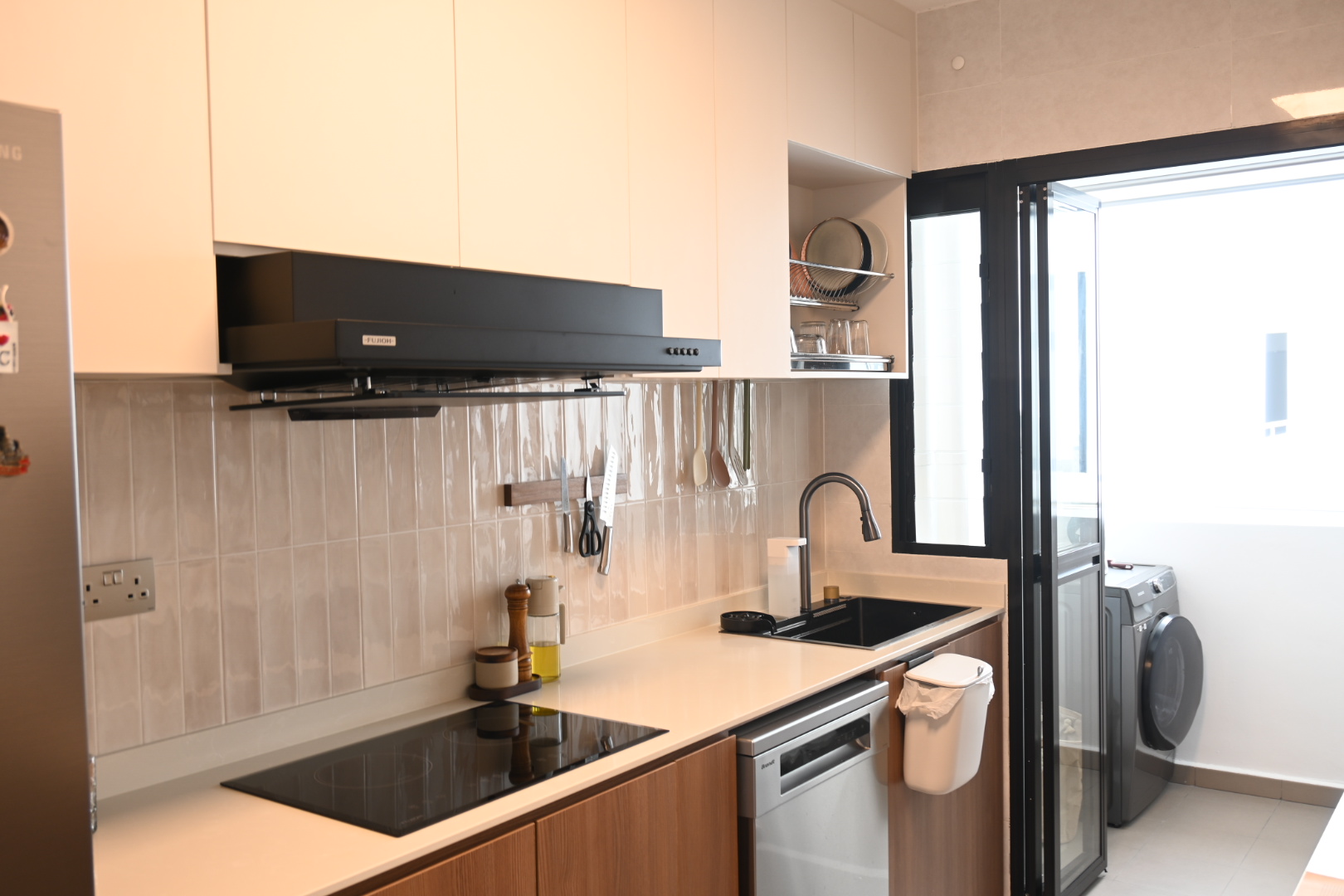 A functional closed kitchen space  - White kitchen cabinets, black range hood, stainless steel dishwasher, beige tiled