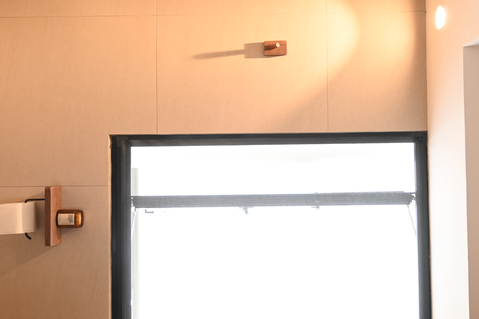 Bali inspired bathrooms  - Wooden wall-mounted dispenser, beige wall, natural light, window with black frame, white paper