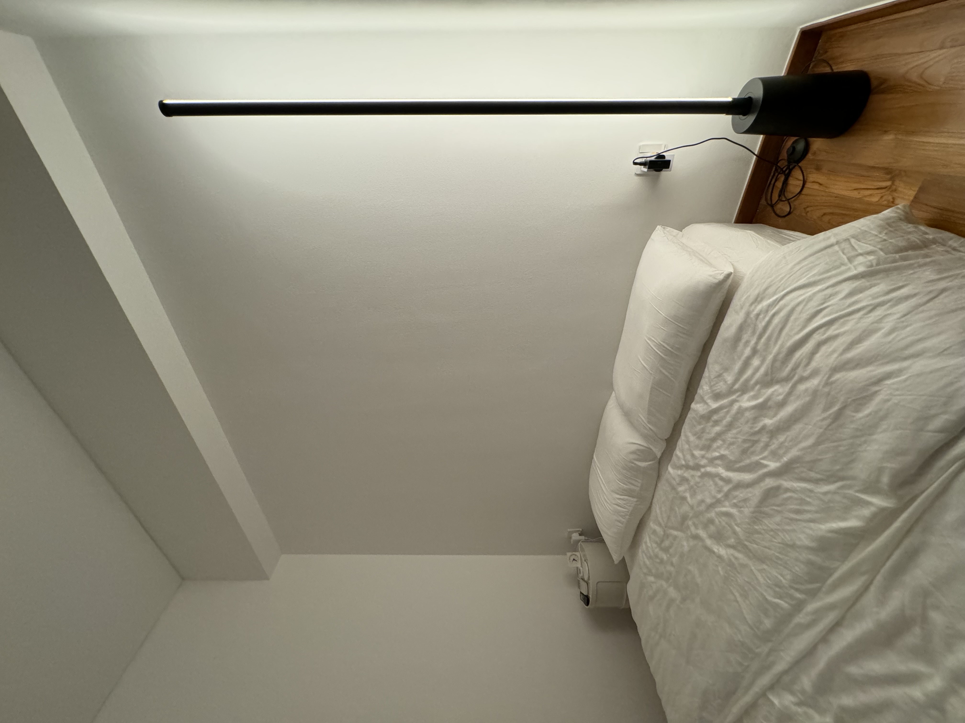 Let There Be Light! - Modern minimalist bedroom, white ceiling, sleek black light fixture, wooden headboard, neatly made bed