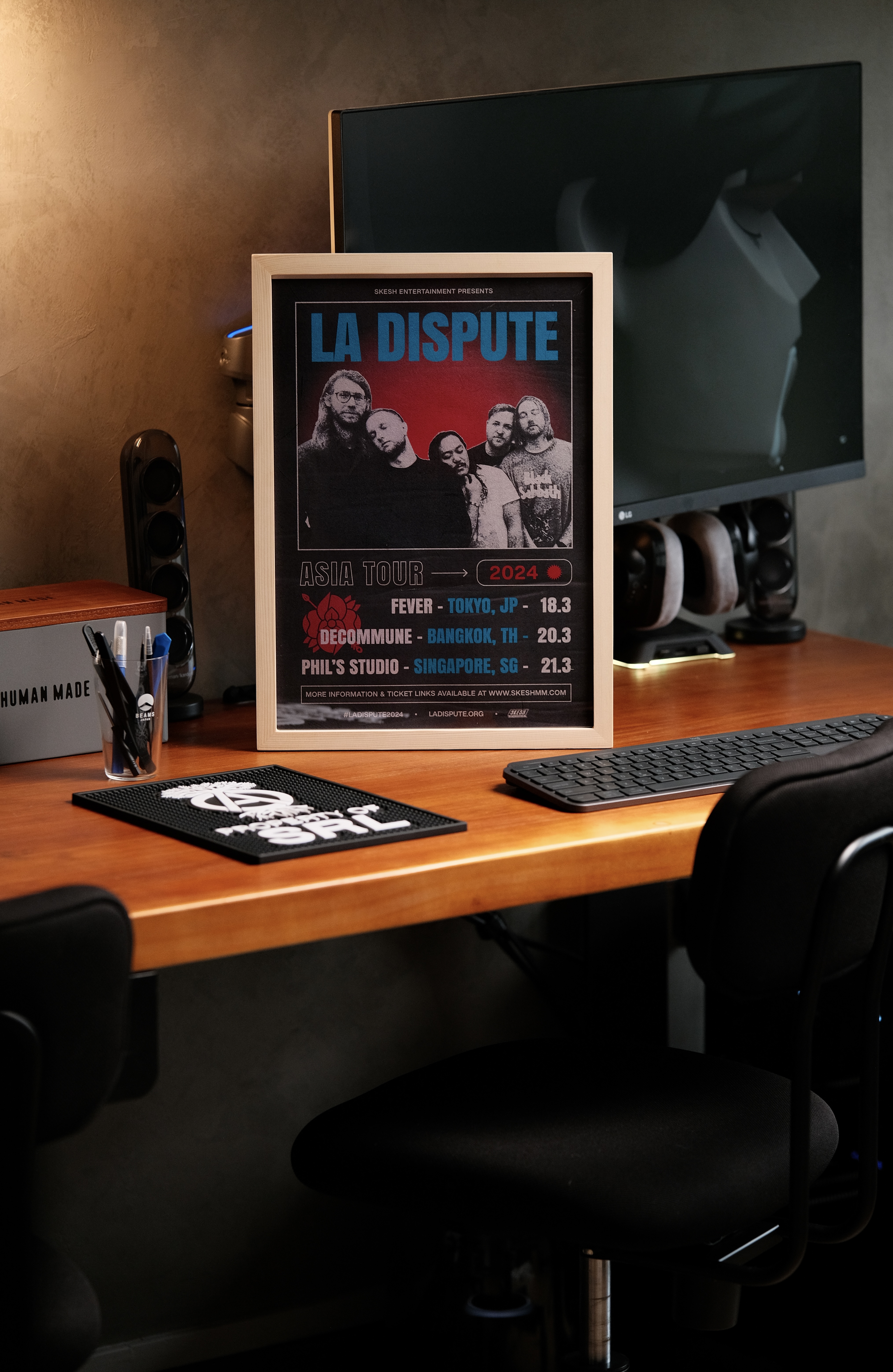 Frame em up! - Modern workspace with sleek black office chair, Framed poster of "LA DISPUTE" band, Wooden desk with ergonomic