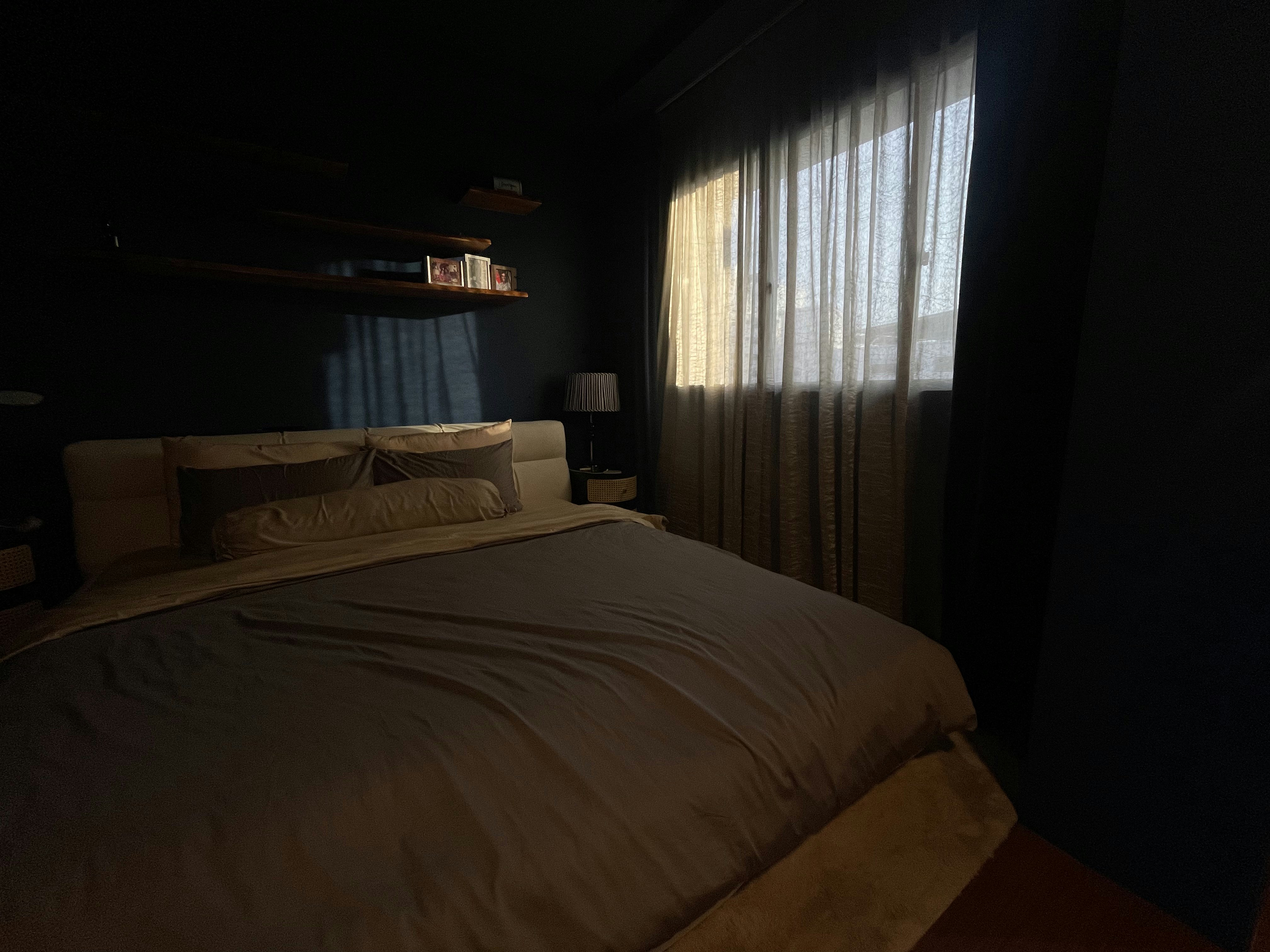 A unique blend of mid-century charm & cottage coziness - dimly lit bedroom, cozy atmosphere, soft lighting, bedside table